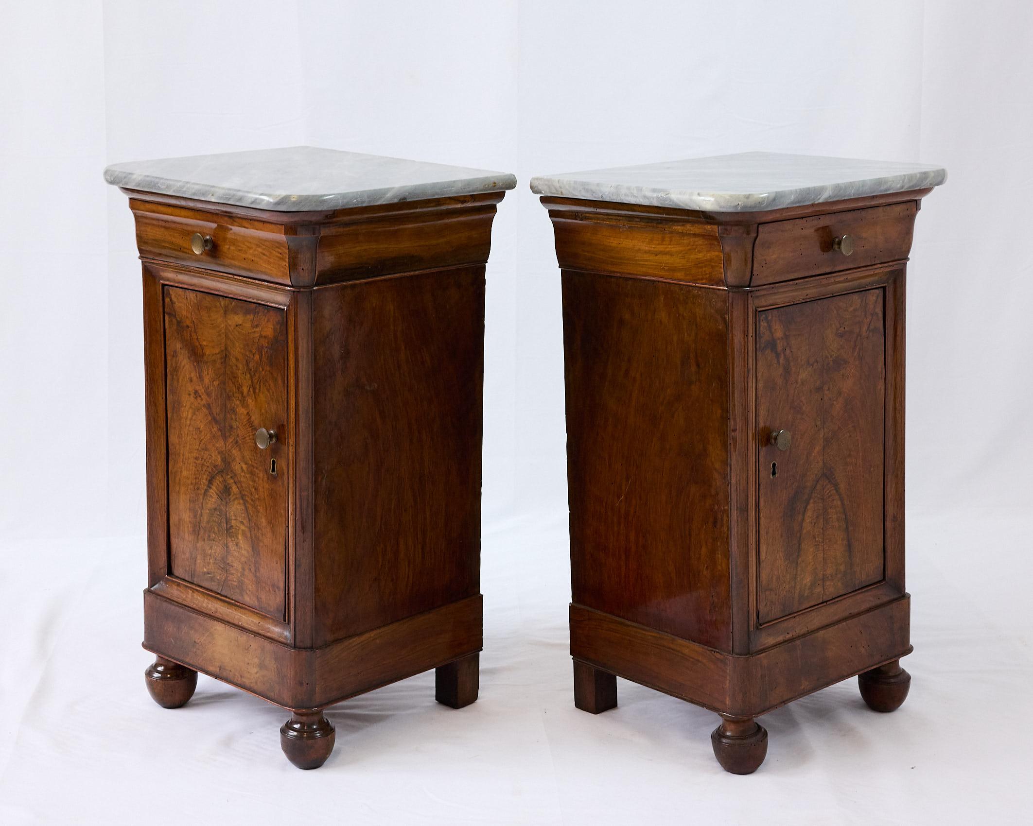 19th Century pair of French bedside cabinets of the Louis Philippe period. Original gray marble tops with curved edges rest on top of facing cabinets, each case containing a drawer over an inset framed door providing ample storage and an interior