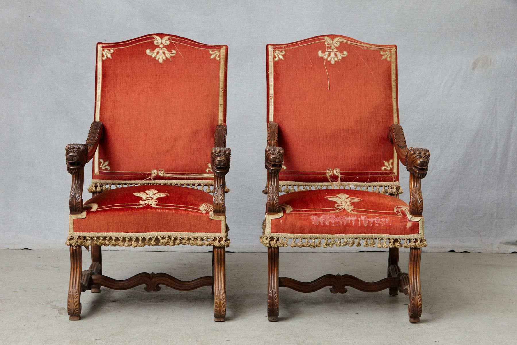 Majestic pair of antique French Louis XIII, Os de Mouton, walnut throne chairs with elaborated carvings, including figural lions head arm rests, carved acanthus-leaves on scrolled arms and feet and legs joined by H-shaped stretchers. The chairs have