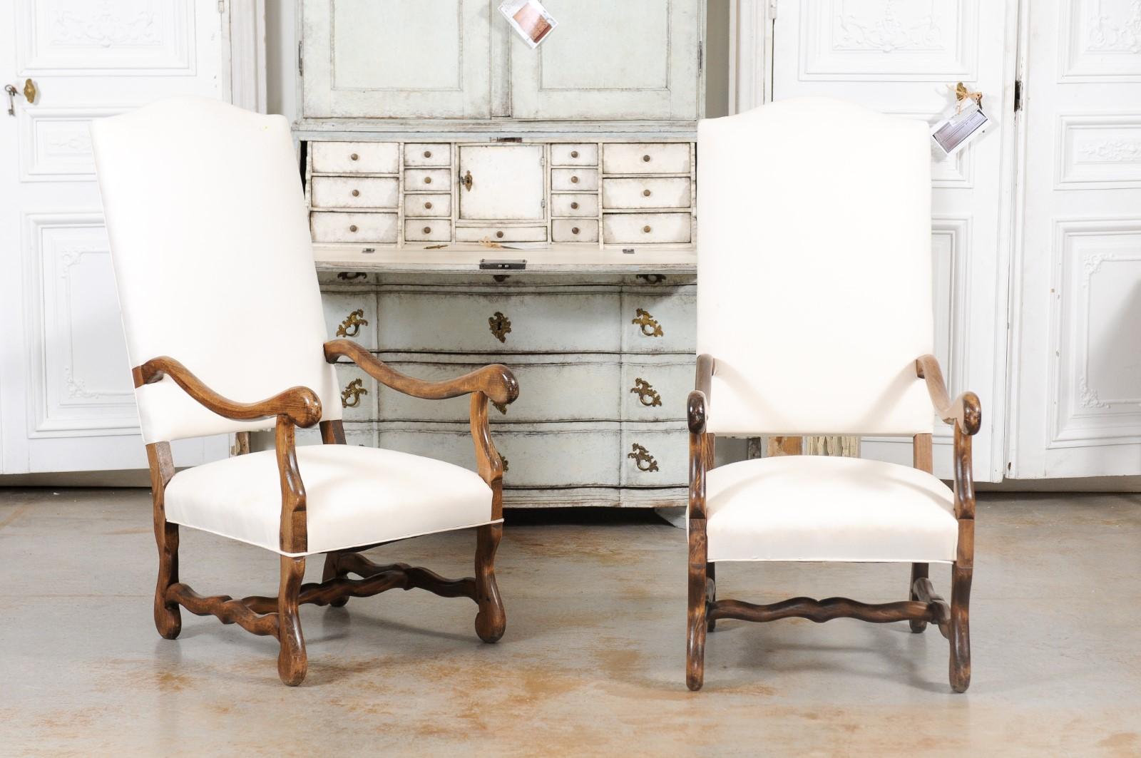 A pair of Louis XIII style os de mouton armchairs from the 19th century, with new upholstery and cross stretchers. Created in France during the 19th century, this pair of ‘os de mouton’ armchairs presents the stylistic of the Louis XIII era. Each