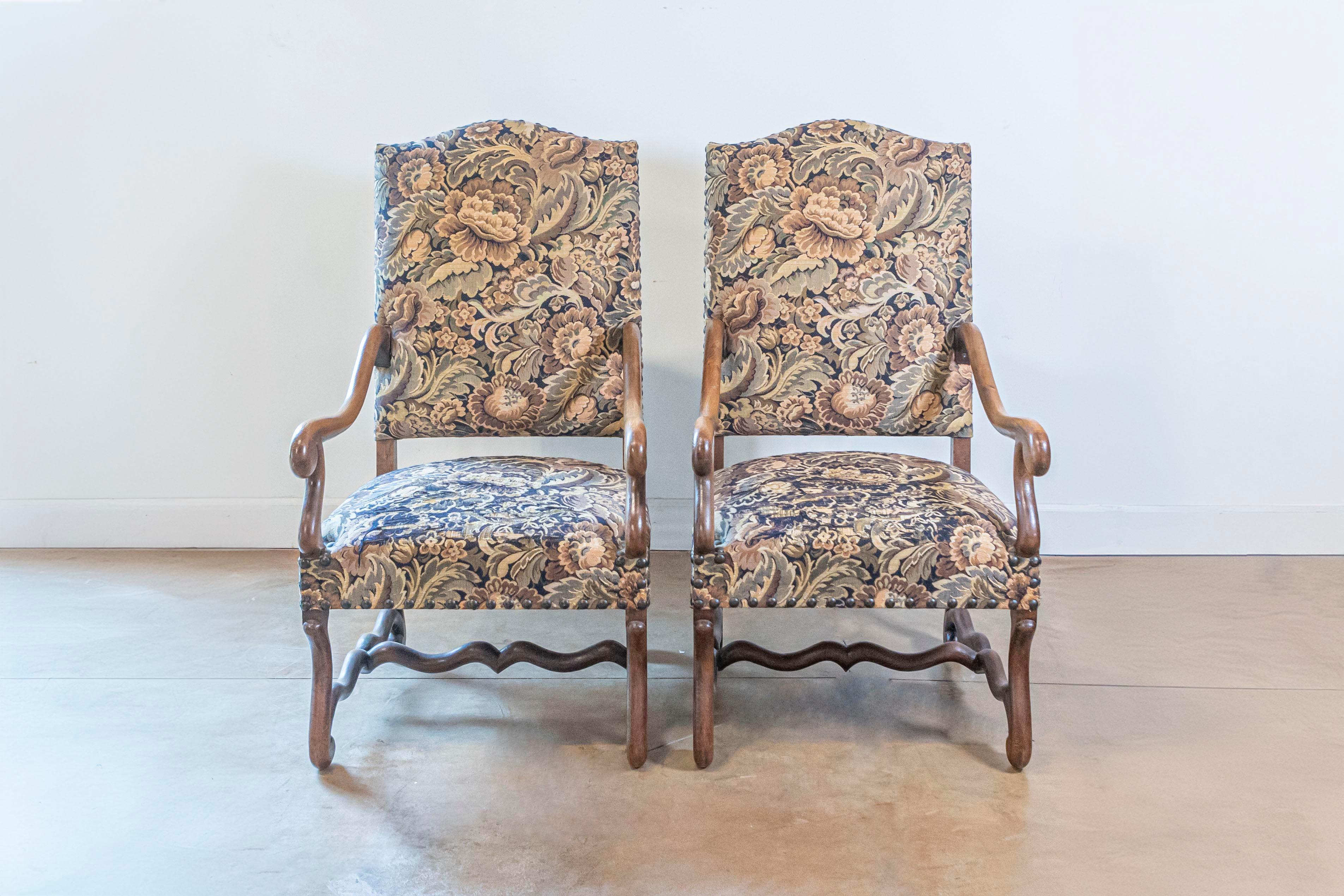 Pareja de sillones franceses Os de Mouton de madera, estilo Luis XIII, del siglo XIX, con respaldo de camello inclinado, grandes brazos con volutas, camillas cruzadas y tapicería usada. Creados en Francia durante el siglo XIX, este par de fauteuils