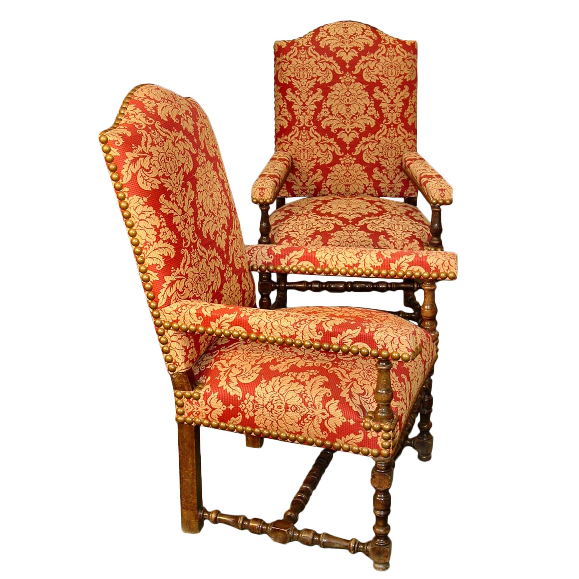 A handsome pair of French Louis XIII st. turn of the century walnut armchairs. Raised on walnut turned legs with a turned stretcher at the front and bottom. Turned baluster supports raise the straight upholstered arms below the high, curved top