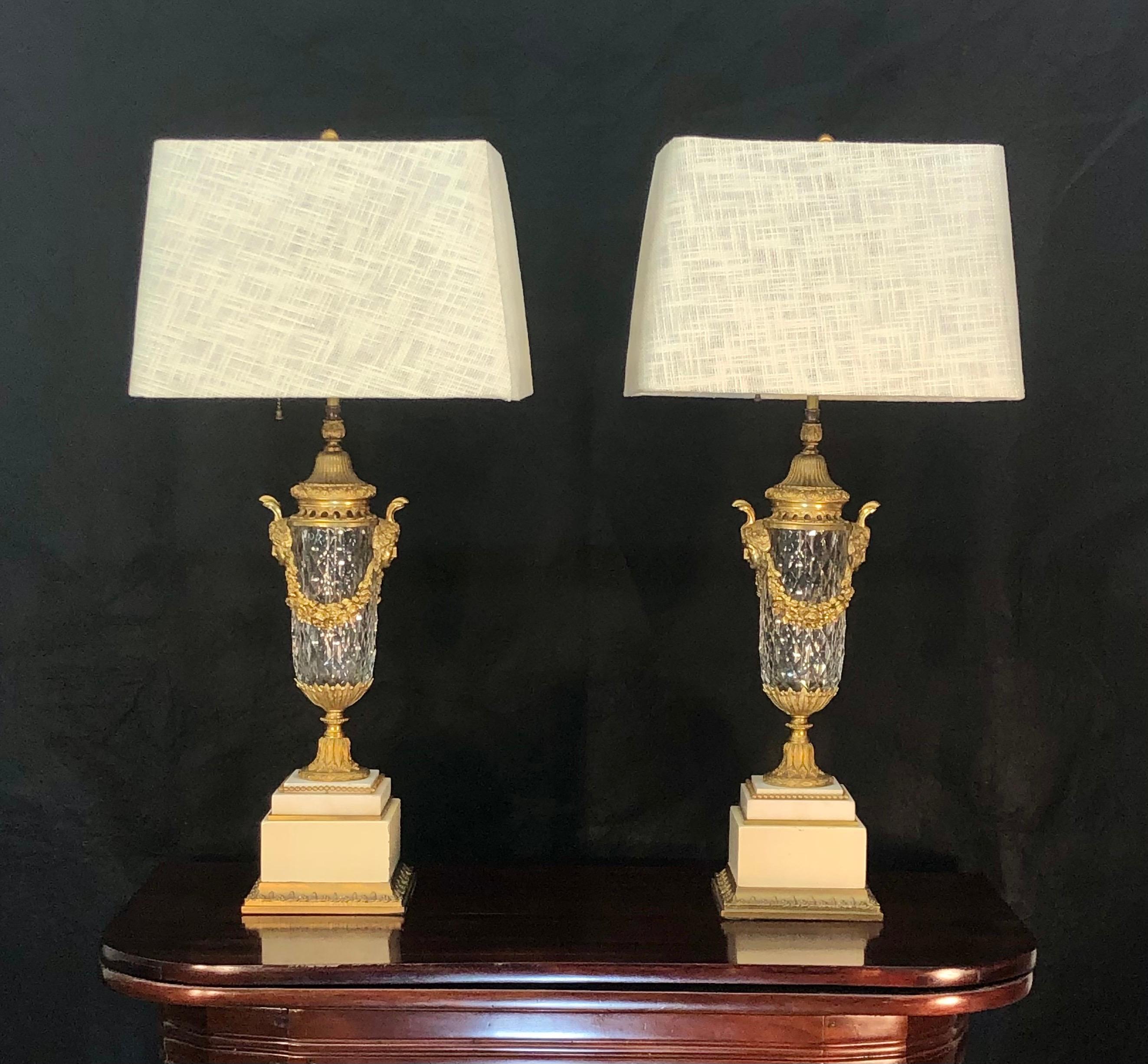 Magnificent pair of French Louis XIV style bronze doré mounted and crystal urns converted to Lamps. The hand-cut crystal urn have a cut diamond pattern with bronze doré mounts on top of marble bases. The original urn was later mounted to a paint