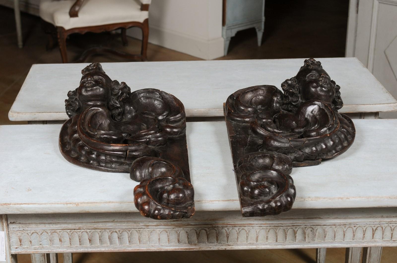 A pair of French Louis XIV period late 17th century carved cherub appliques from Strasbourg, with scrolling design. Born in the Alsacien city of Strasbourg in 1690s (which was annexed by French King Louis XIV in 1681), each of this pair of appliques