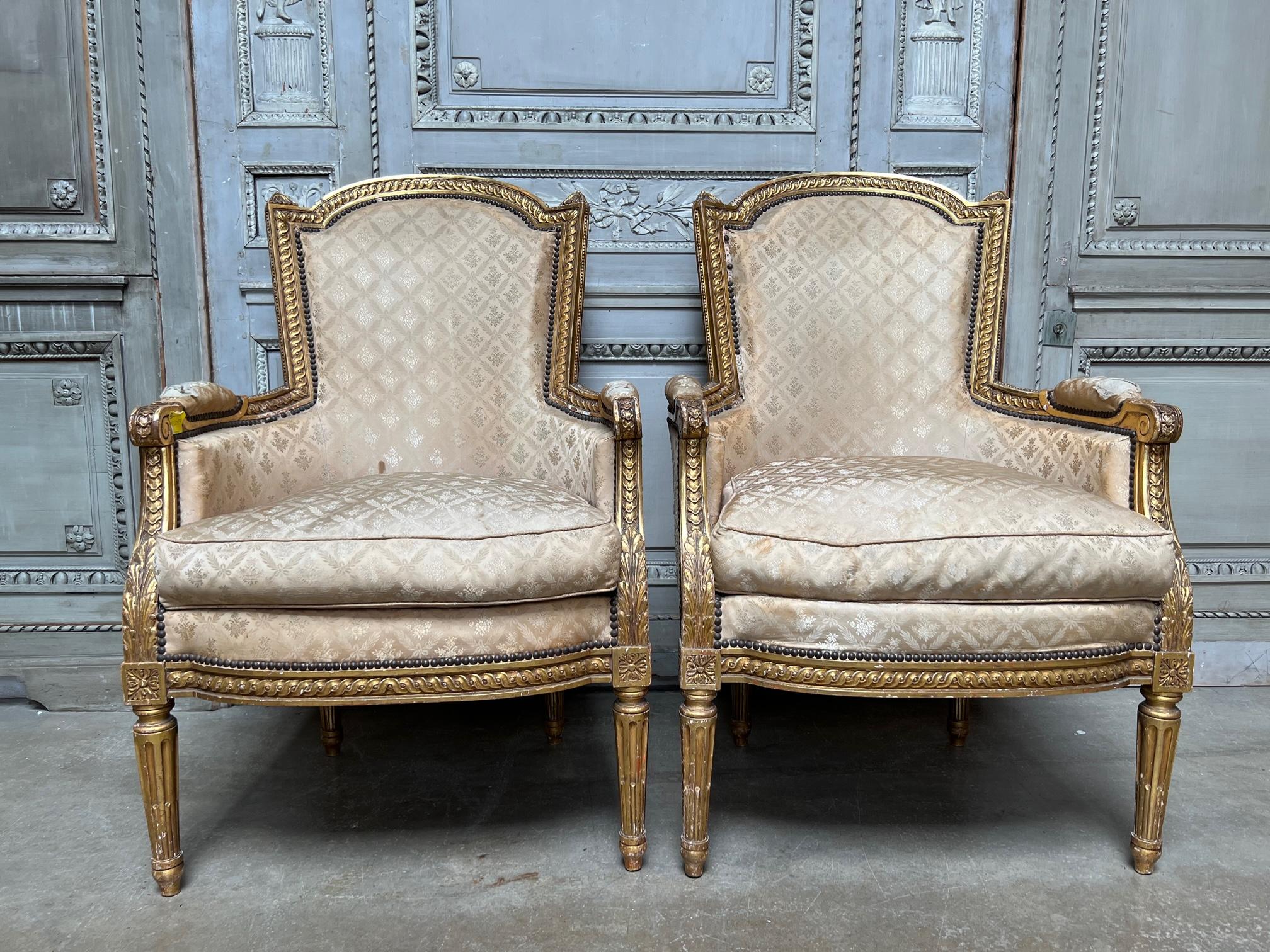 A very large pair of giltwood bergeres with a hod shaped back and deeply carved gadrooning beading and fluted legs. These great chairs date from the late 19th up until the 1920s, so we dated them 20s to be on the safe side. They are a very nice