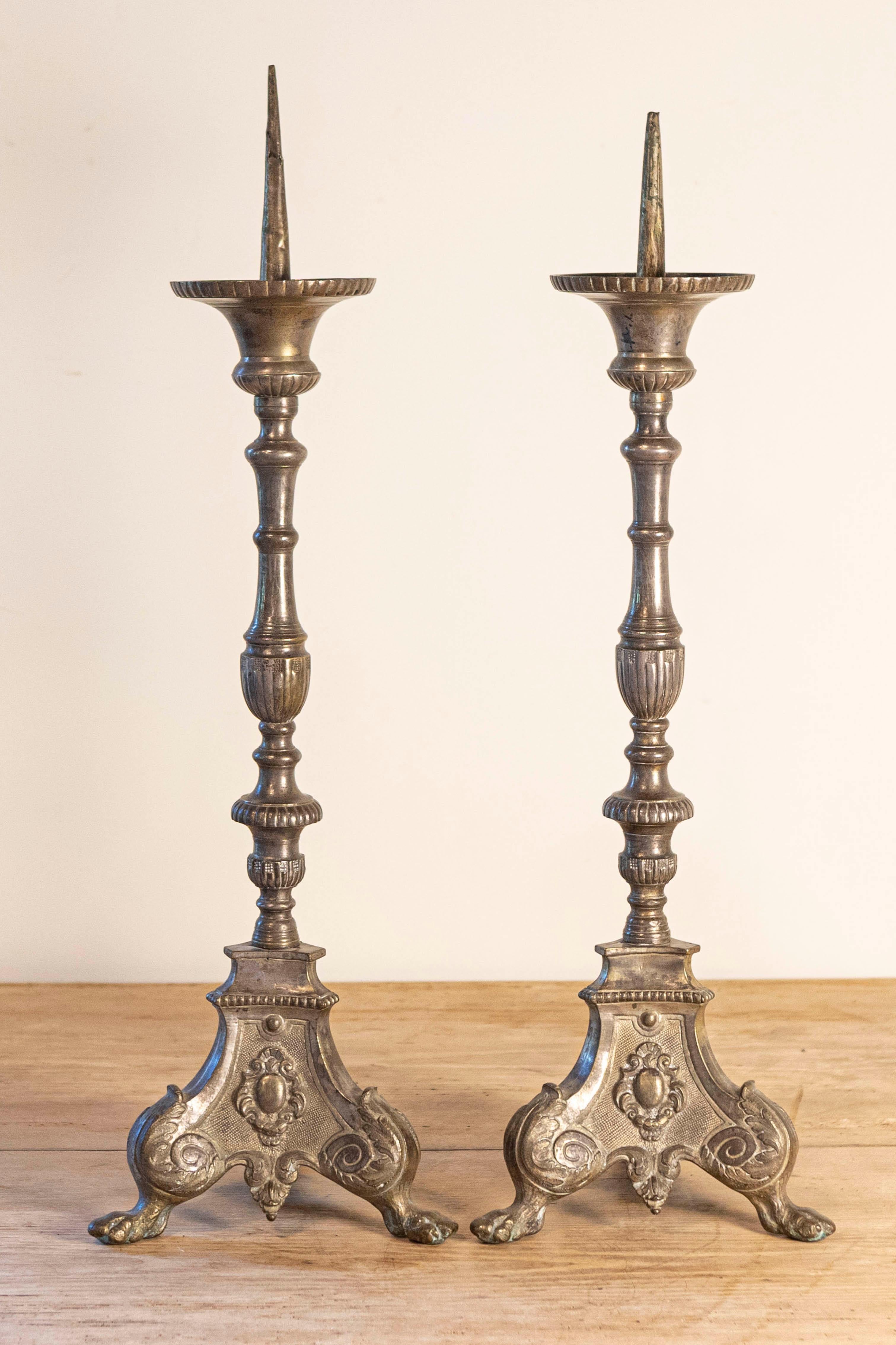 Coppia di candelieri francesi Luigi XV in bronzo argentato del XVIII secolo, con volute e piedi a zampa. Nata in Francia durante il regno del re Luigi XV, soprannominato l'Amato, questa coppia di candelieri in bronzo argentato è caratterizzata da