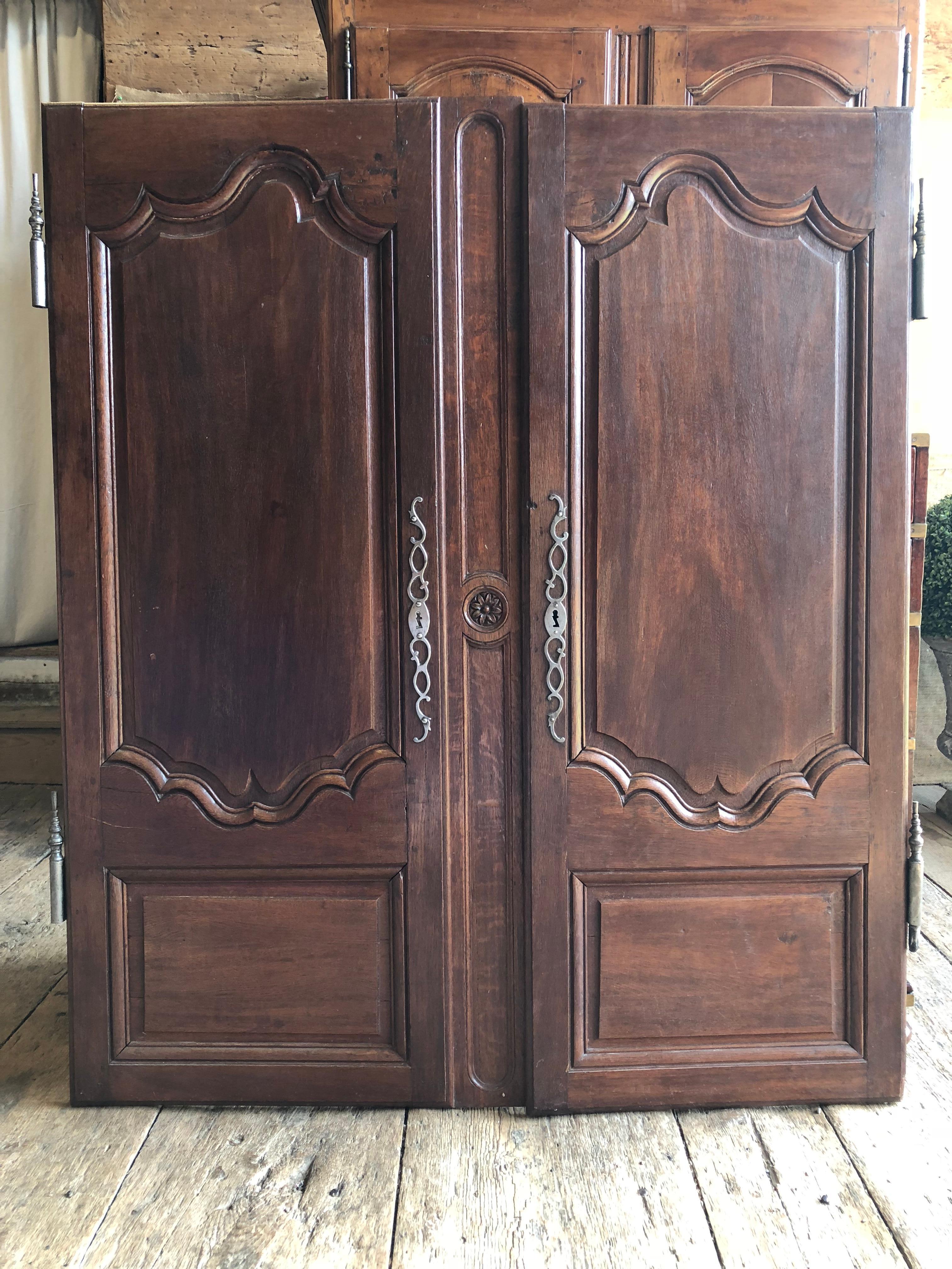 A pair of French Louis XV armoire doors in oak, circa 1790, nicely panelled and retaining their original steel hardware.
The centre divider (currently attached to the lady side door) can be removed to create a pair of equal sized doors. Width