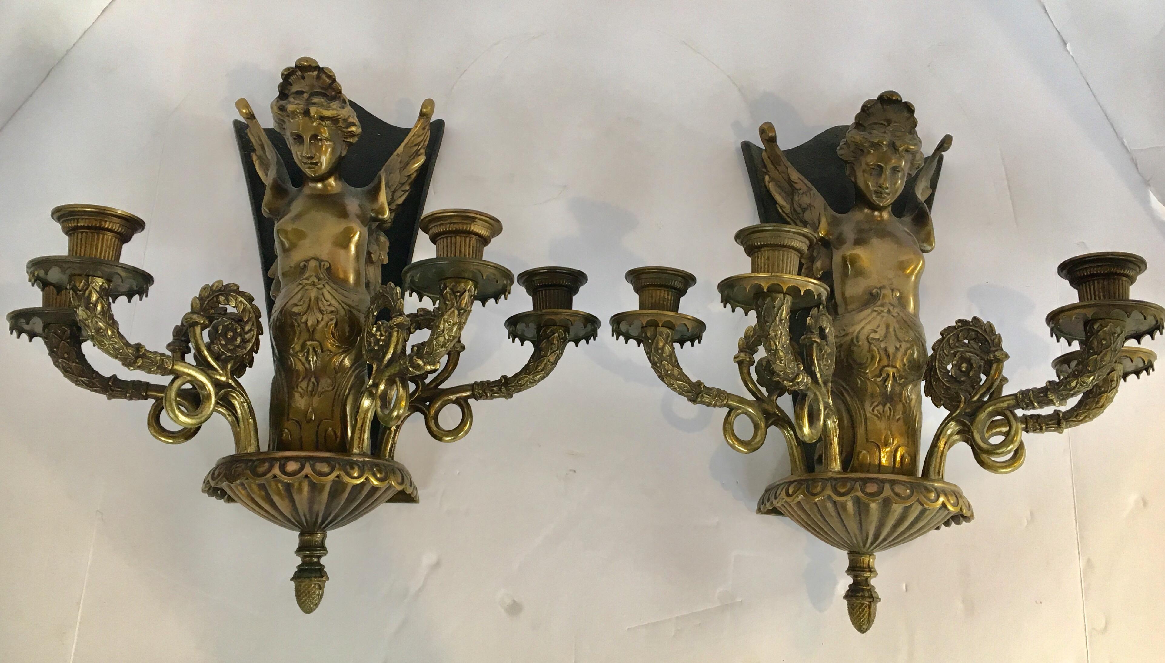 Gorgeous pair of matching heavy bronze wall sconces with four arms each. At center is a winged, topless woman.