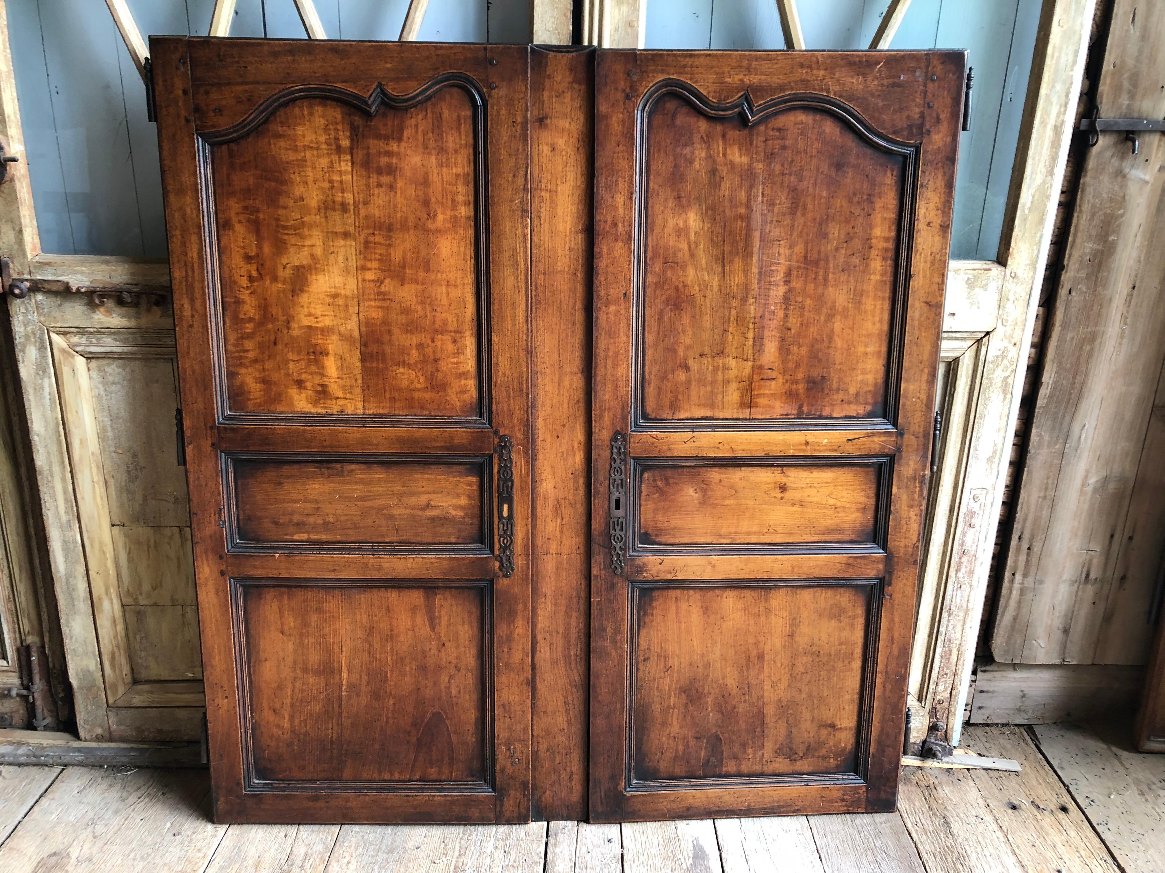 A pair of French Provincial cabinet doors in walnut, Louis XV period circa 1770, with iron hardware. Nice patina. 
Each door is 25” wide x 59” height. The center divider is 5” wide and is attached to the left door but is removable.
 