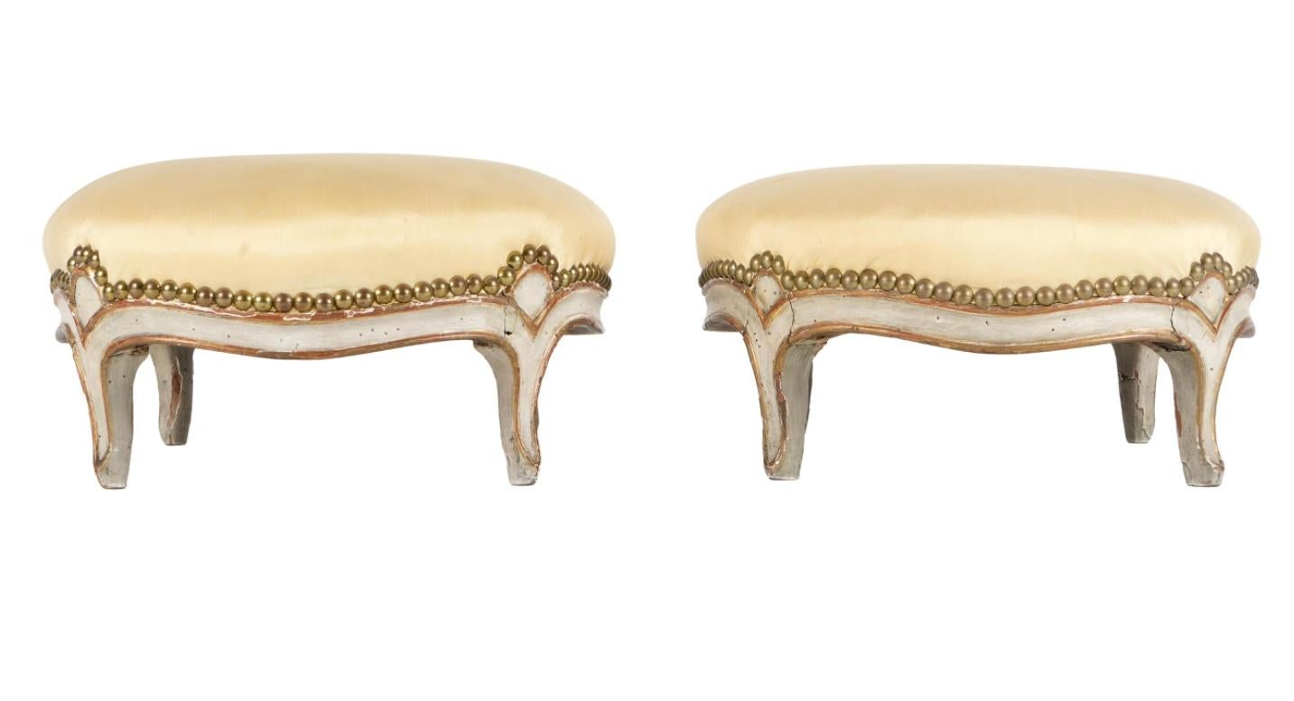 This is a beautiful pair of French Louis XV style stools from the 19th century, carved and painted serpentine frame and legs with yellow silk upholstery and nail head trim. Solid and sturdy this is a rare pair of matching stools in original painted