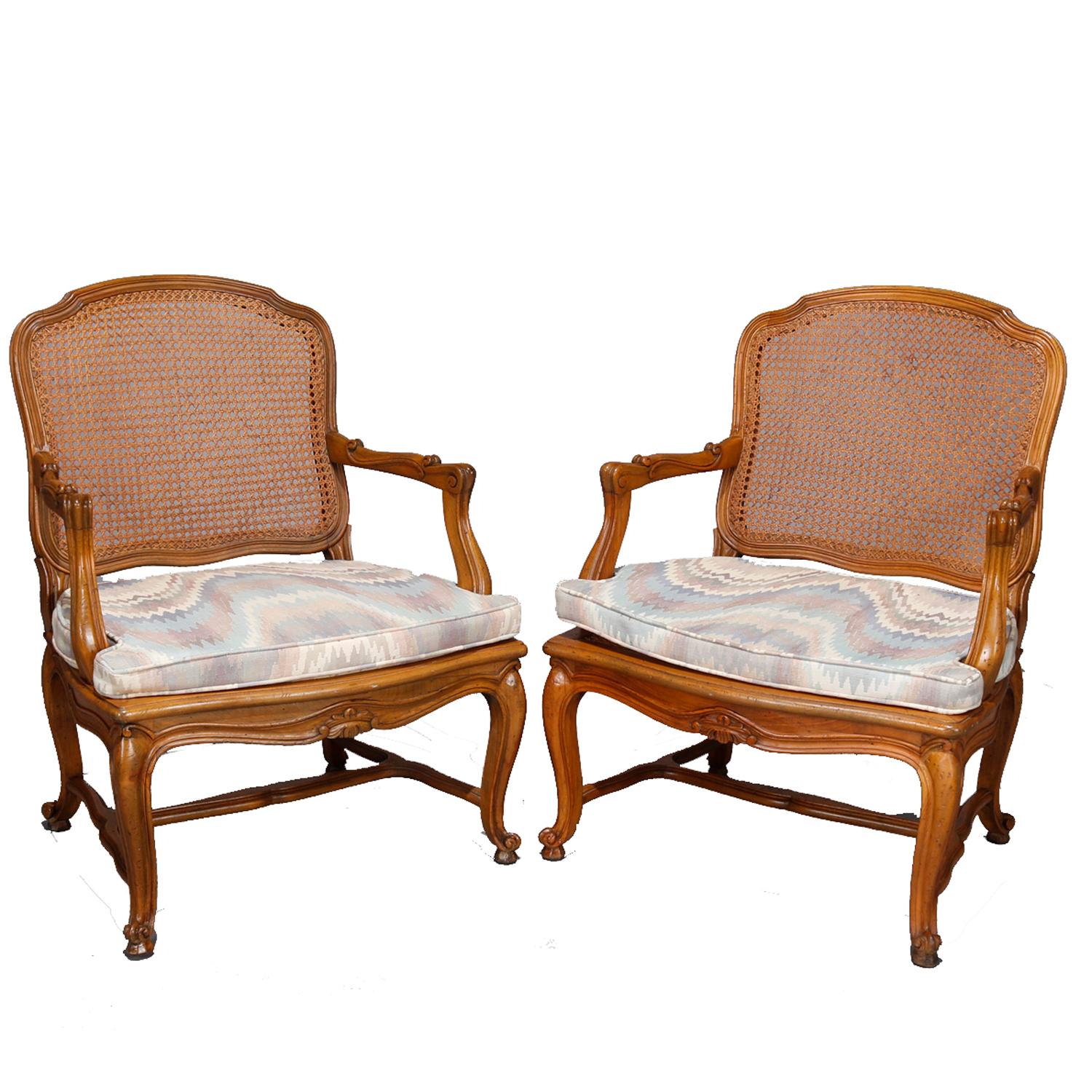 A pair of antique French Louis XV armchairs offer carved fruitwood frames with caned seats and backs, raised on cabriole legs terminating in scroll feet, chair pads included, 19th century

***DELIVERY NOTICE – Due to COVID-19 we are employing