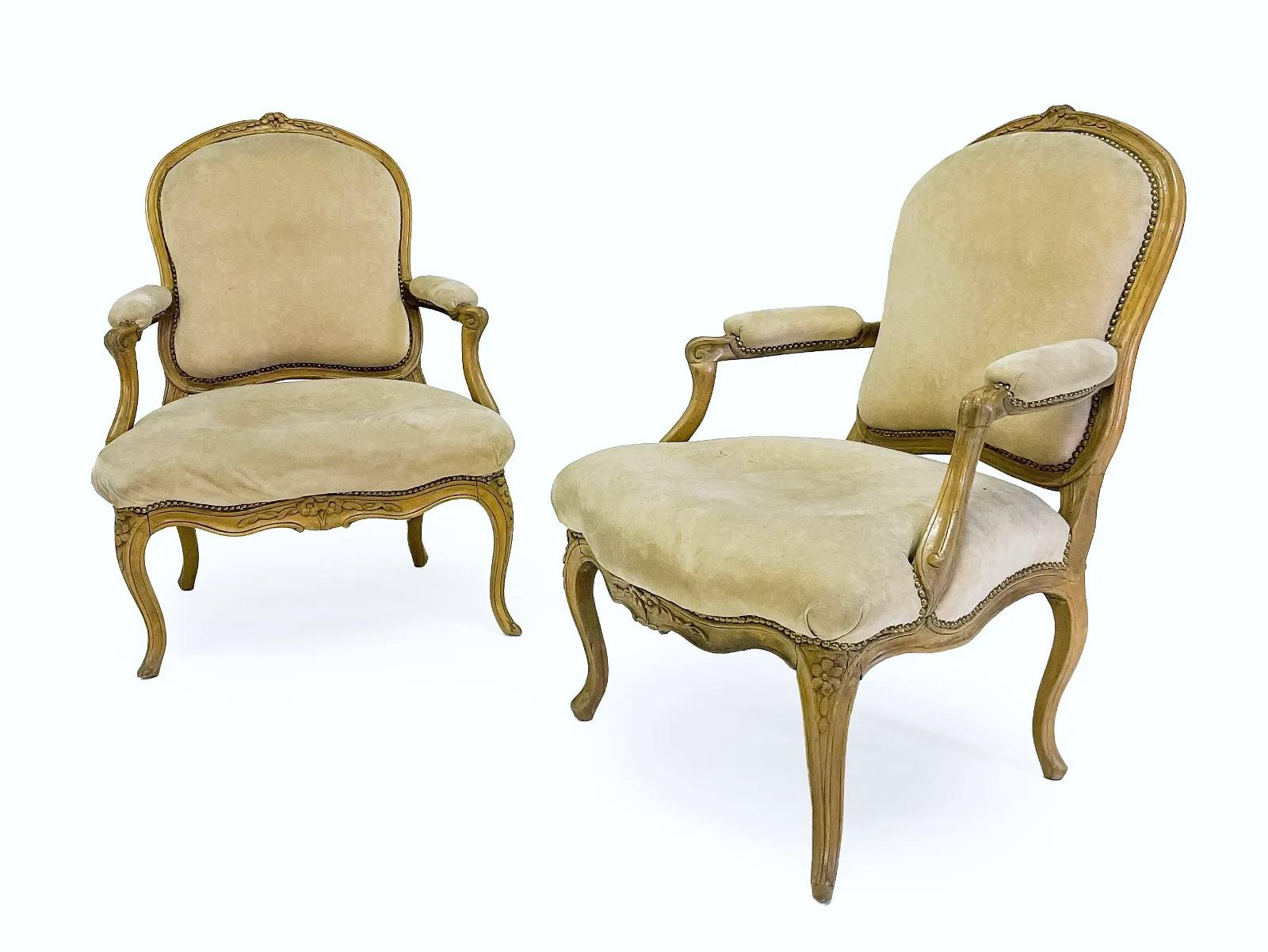 A fine larger-scale pair of Louis XV fauteuils in beech, backs and seats upholstered in tan fabric, the frames nicely carved with floral and other motifs, with cabriole legs scalloped apron.
