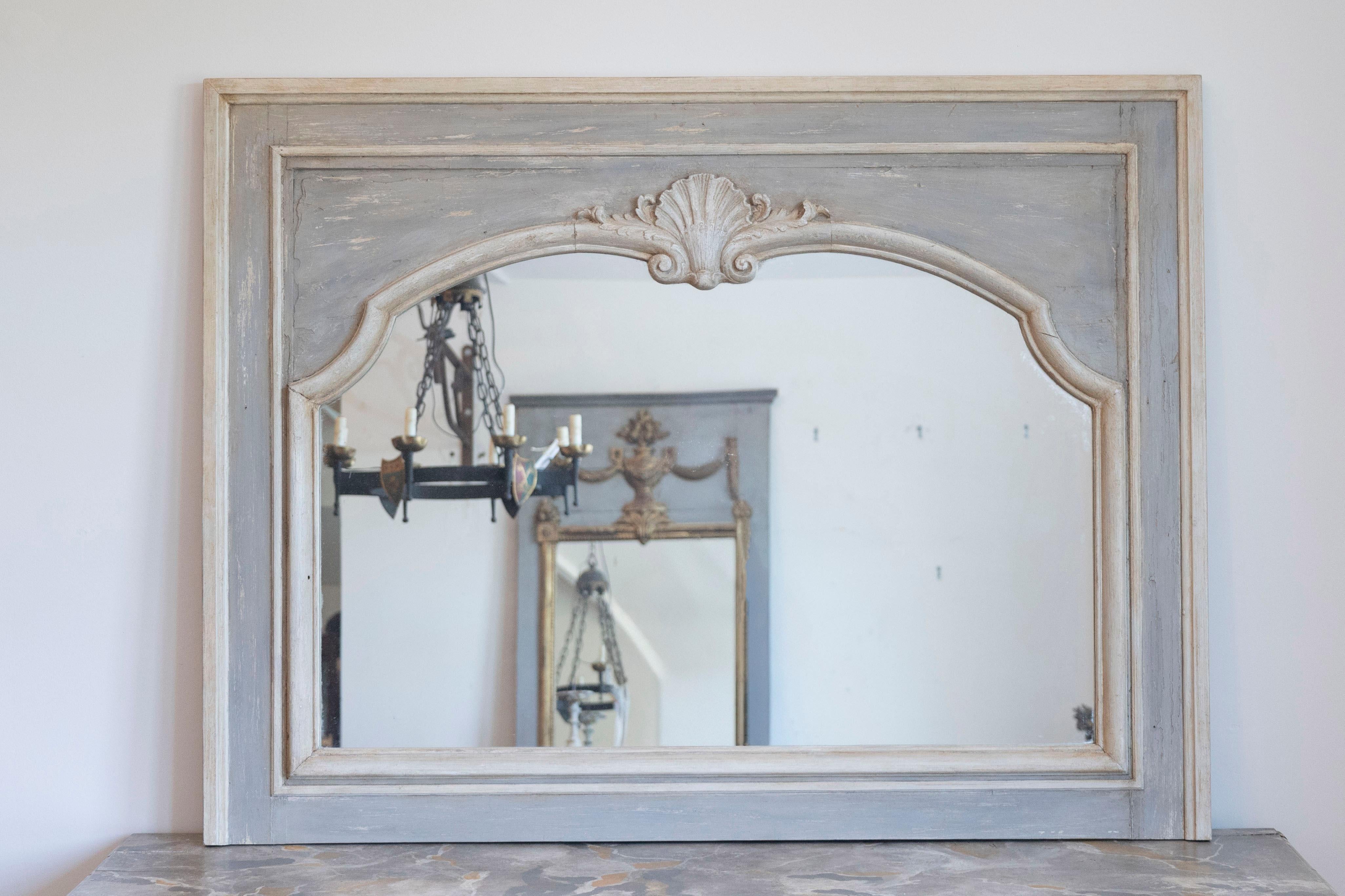 A pair of French Louis XV style painted wood horizontal mirrors from the late 19th century with carved shell motifs. Each of this pair of mirrors features a horizontal Silhouette, painted in a light grey color and accented by cream highlights. Image