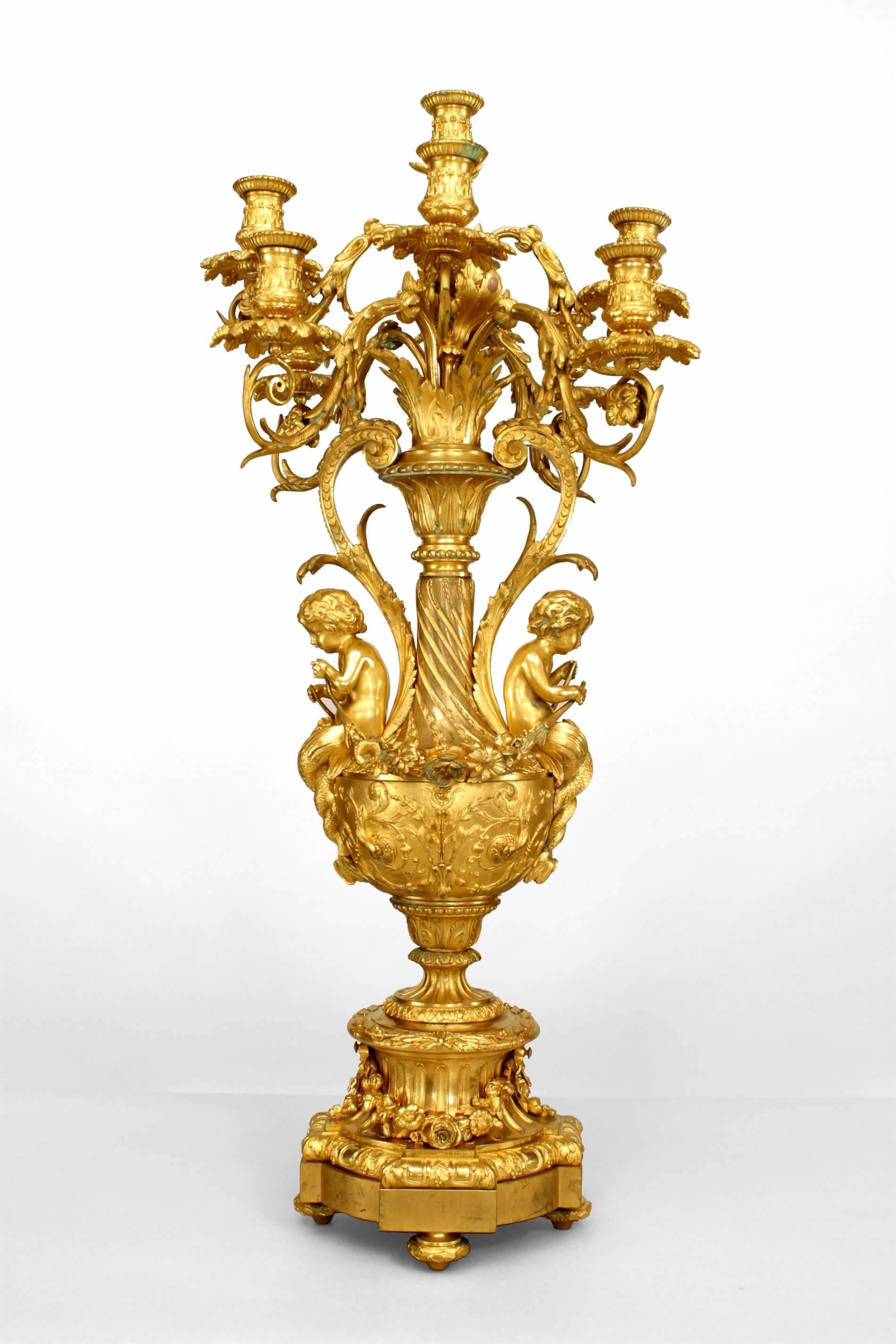 Zwei französische 9-armige Kandelaber aus Bronze im Louis-XV-Stil (19. Jh.) in Form einer Urne mit gerollten Armen und 2 Amoretten, die Girlanden halten. (PREIS ALS PAAR)
