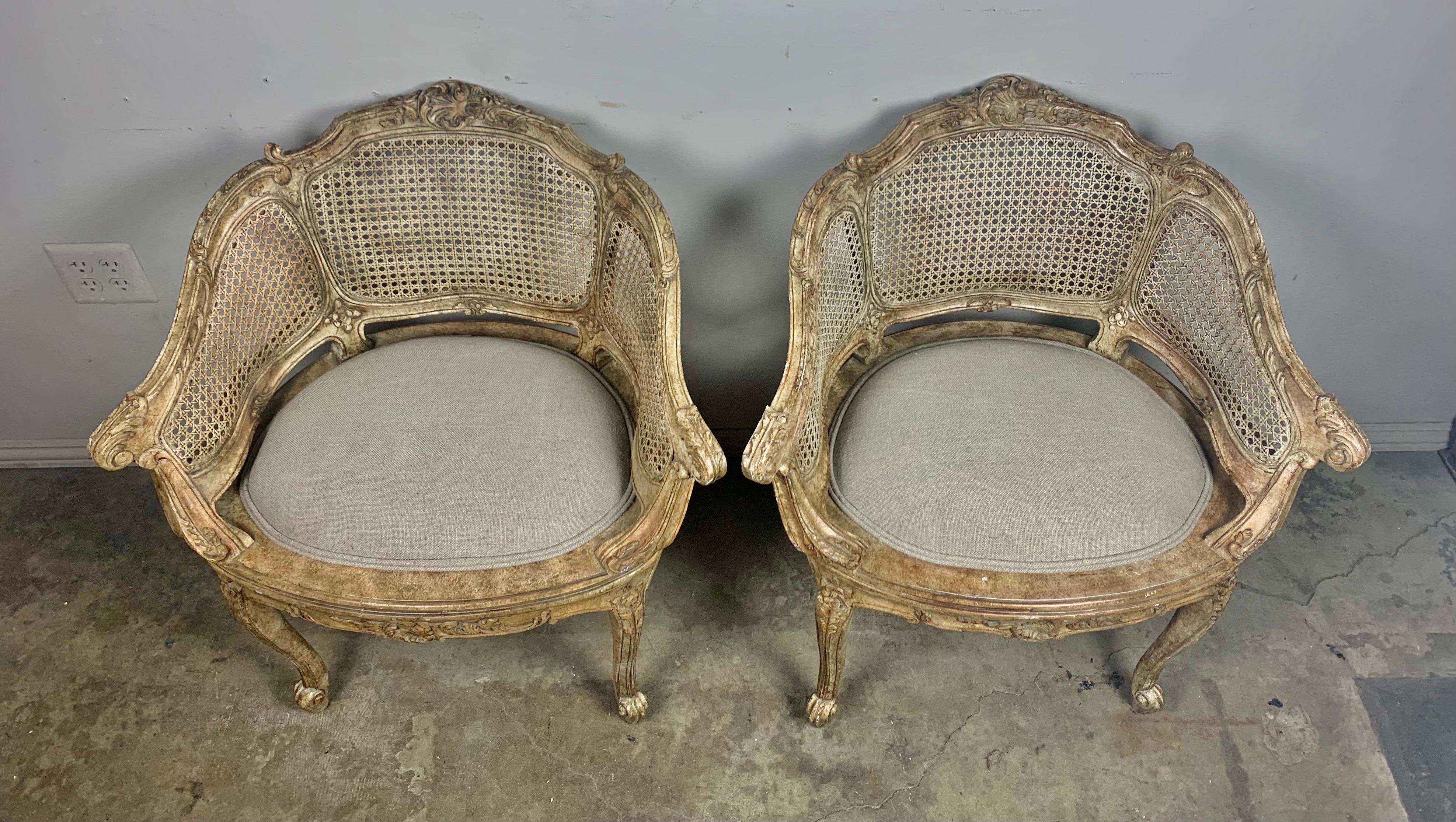 Pair of charming French Louis XV style cane armchairs that stand on four cabriole legs. This pair would be perfect in a small sitting area or as vanity chairs in your master bath. The chairs are newly upholstered in Belgium linen and ready to
