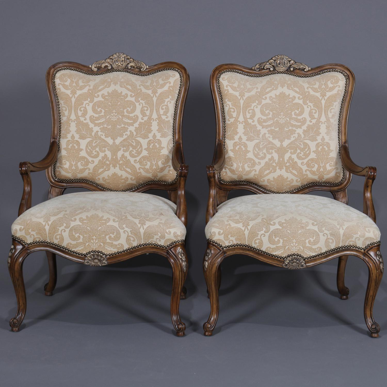 A pair of French Louis XV style carved and upholstered fauteuils feature carved mahogany frames having gilt foliate crest and apron, scroll arms and raised on cabriole legs, 20th century

Measures: 44