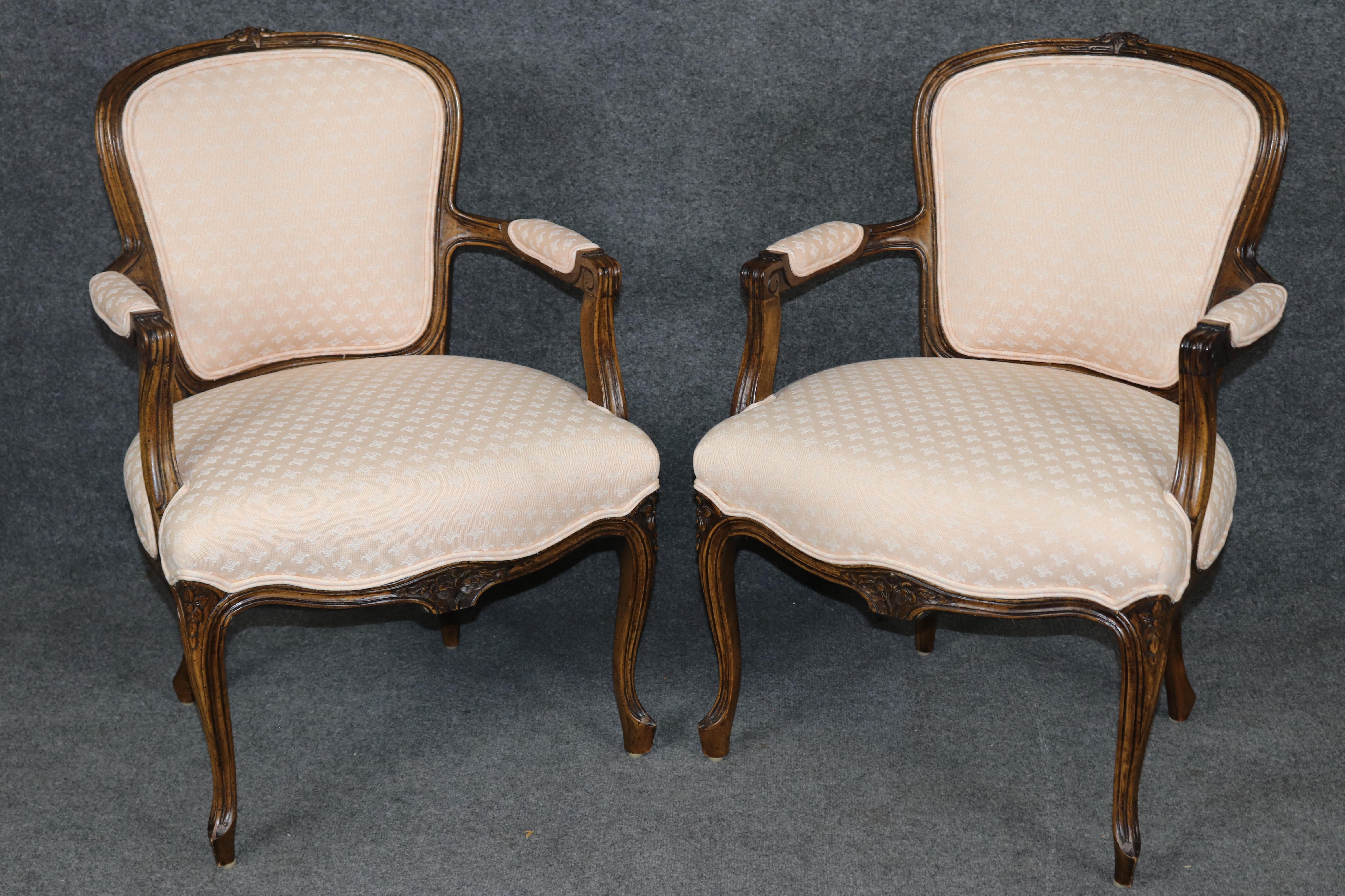 Dimensioni - H. 32 in L: 22 in D: 21 1/2 in SH: 17 1/2 in 

Un'elegante coppia di poltrone in noce intagliato in stile French Rococo XV, finemente lavorate tra la prima e la metà del XX secolo e che riflettono la raffinatezza senza tempo del design