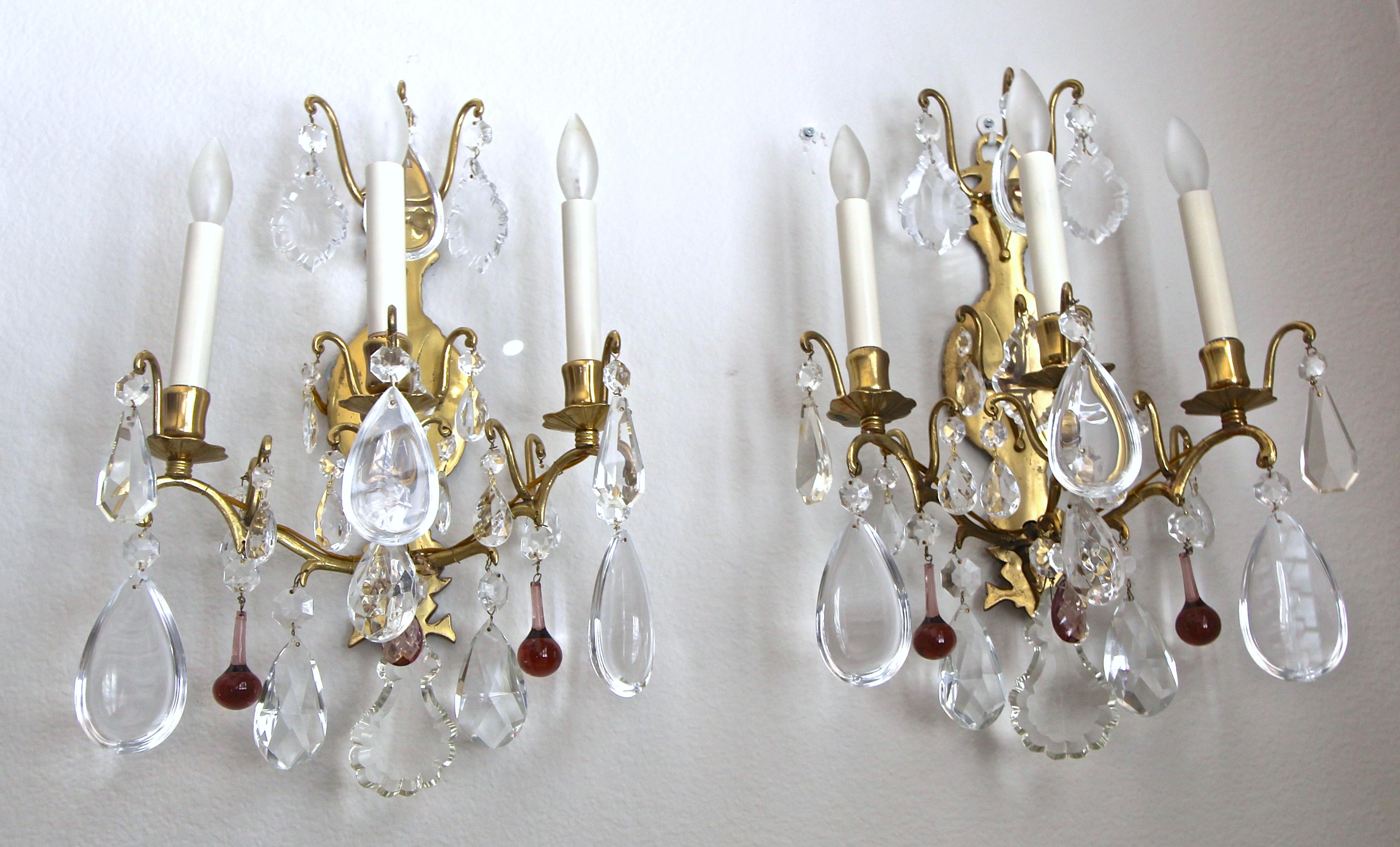 Pair of three-light French Louis XV style wall sconces with crystal pendalogues and amethyst droplets on a brass frame.