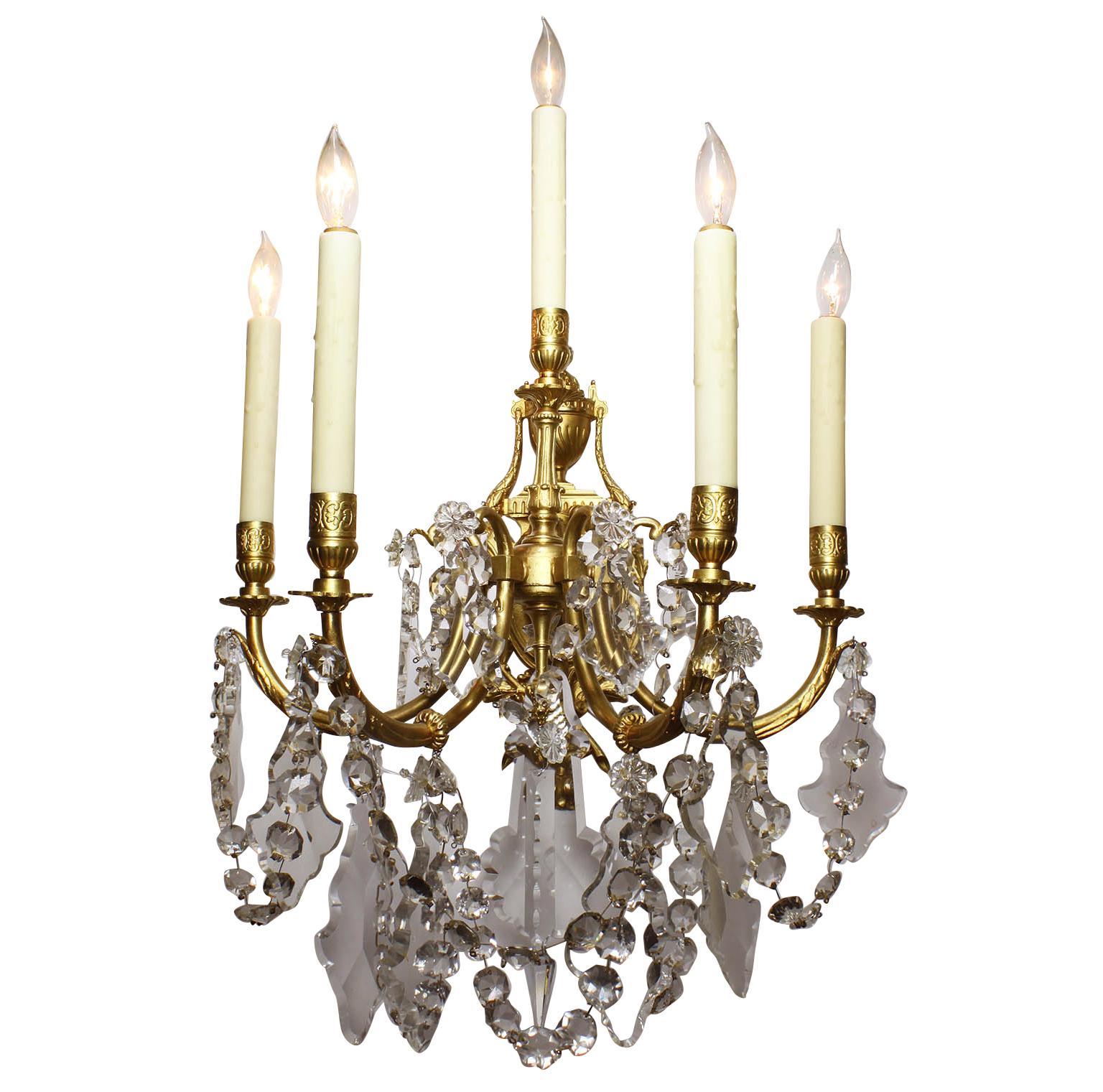 Pair of French 19th-20th century Louis XV style gilt-bronze and cut-glass five-light wall lights sconces. The shield-shaped back-plate crowned with an urn and surmounted with five scrolled candle arms, Paris, circa 1900. 

Measures: Overall height