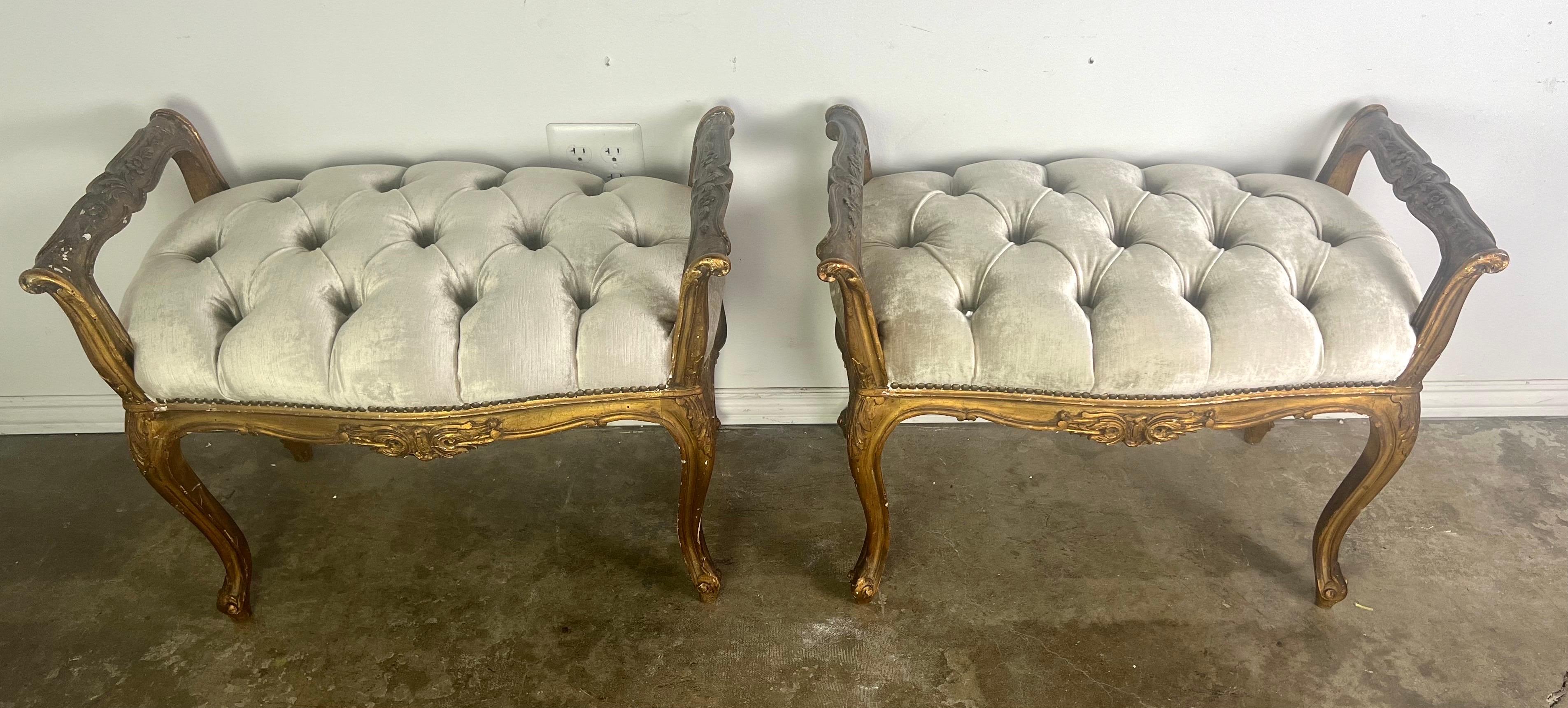 Pair of French Louis XV style gilt wood benches. Each bench features elegantly carved gilt wood frames with intricate detailing, including scrolls and floral motifs, which highlight the craftsmanship typical of French furniture design.  The benches