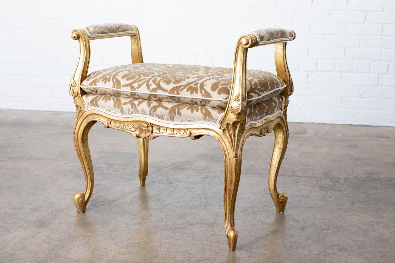 Gorgeous pair of French carved giltwood vanity benches or window benches. Made in the grand Louis XV style featuring a Fortuny style print of floral vines in velvet. The benches have a beautiful aged patina with desirable wear and fading on the