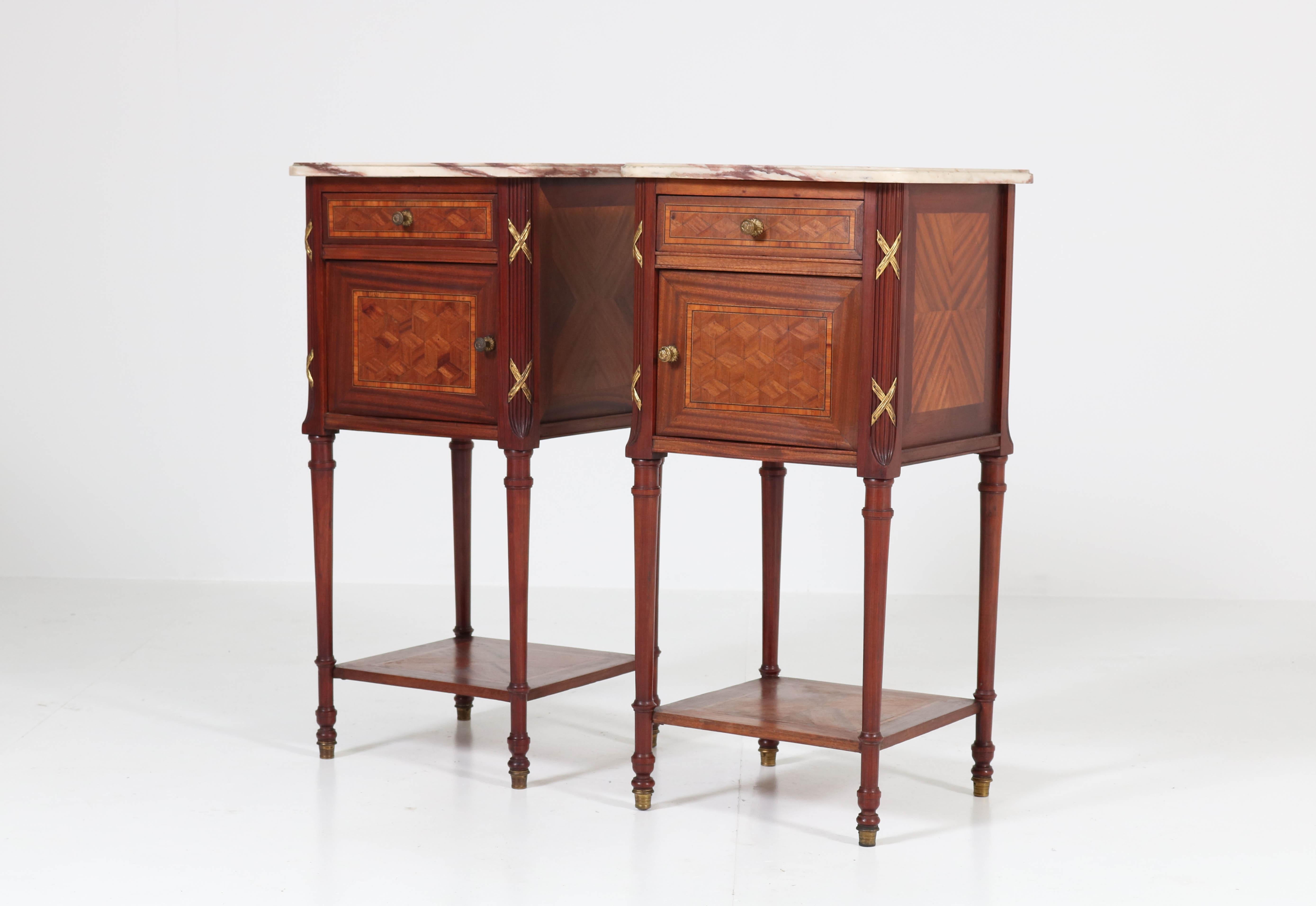 Stunning and elegant pair of Louis XV style nightstands or bedside tables.
Striking French design from the 1920s.
Mahogany with marquetry and bronze garniture.
Original marble tops.
In good original condition with minor wear consistent with age