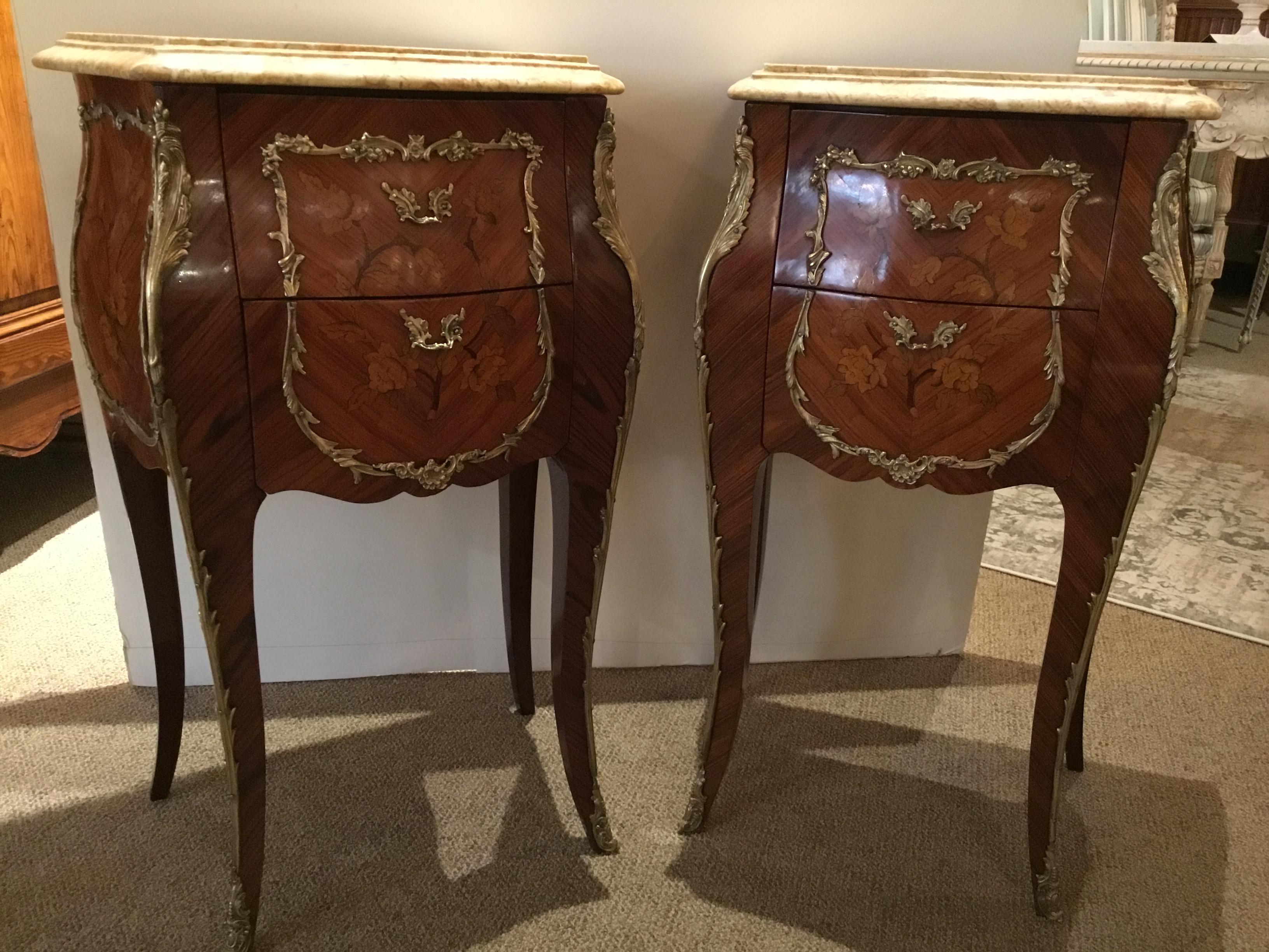 Pair of French Louis XV-style cream marble top nightstands, 20th century, shaped marble top with
molded edge, over case with floral marquetry, gilt metal mounts, fitted with two drawers,
rising on French bracket feet.