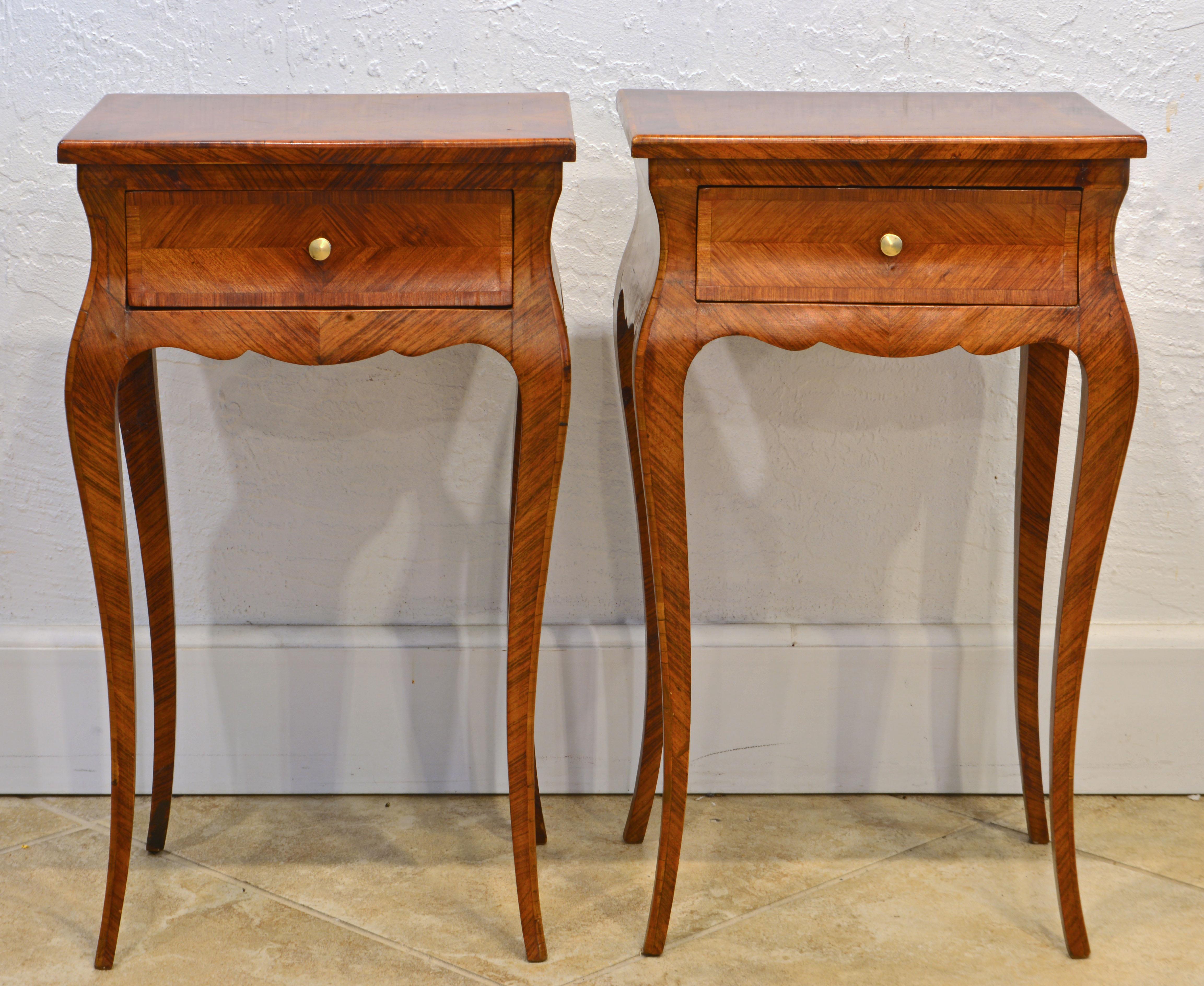 Elegant lines, petite proportions and parquetry surfaces make this pair of French Louis XV style petite commodes especially attractive. The tops centering a ribbon inlay have a drawer underneath and the scalloped aprons continue in the four cabriole