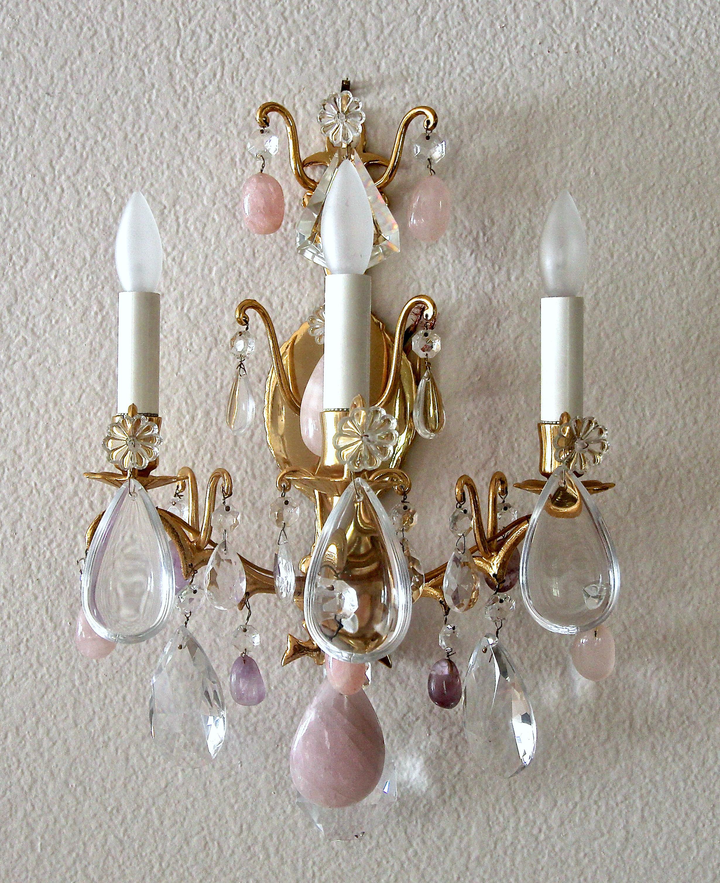 Pair of three light French Louis XV style wall sconces with combination of lavender and pink rock crystals and crystal pendalogues on a brass frame.