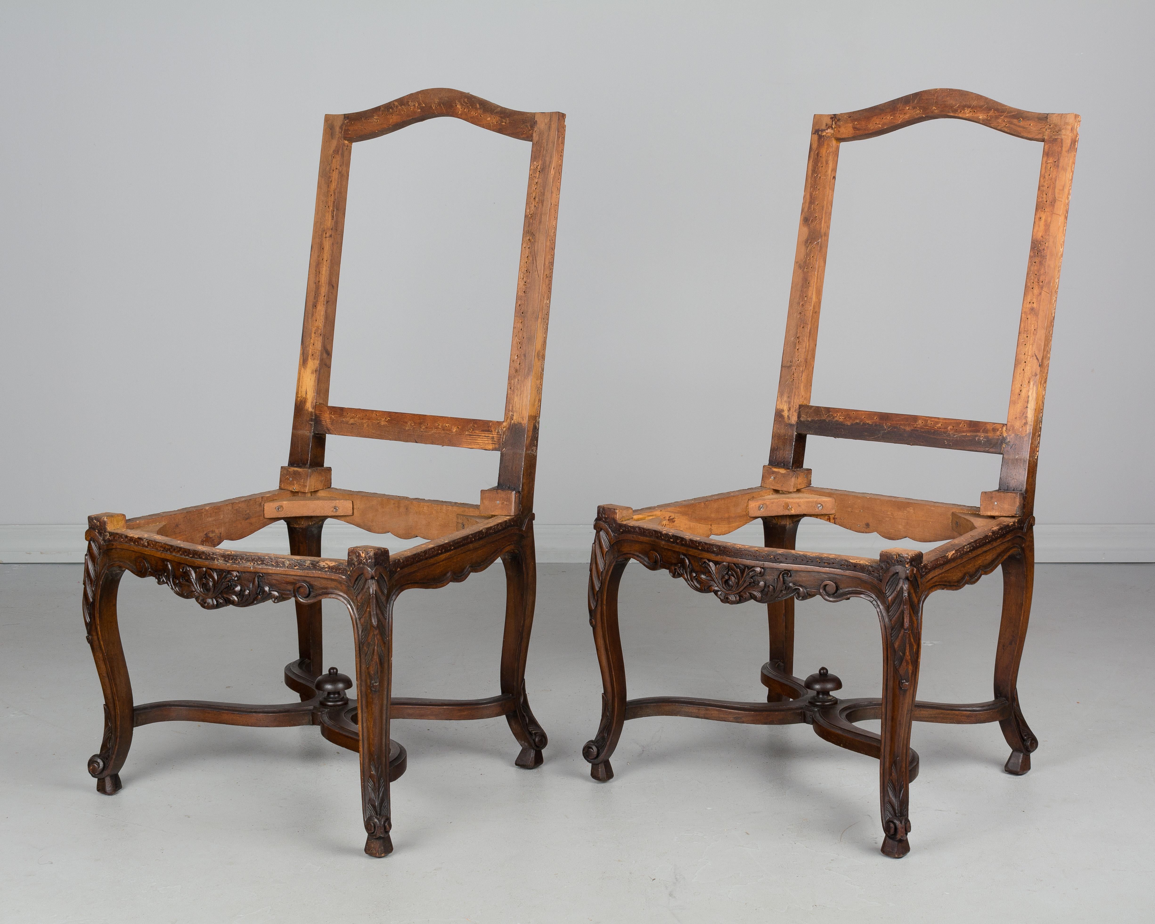 Pair of French Louis XV Style side chair frames made of solid walnut with nice hand-carved decoration and x-stretchers with finial detail. Sturdy frames, stripped of old upholstery and sold as is. Waxed finish.