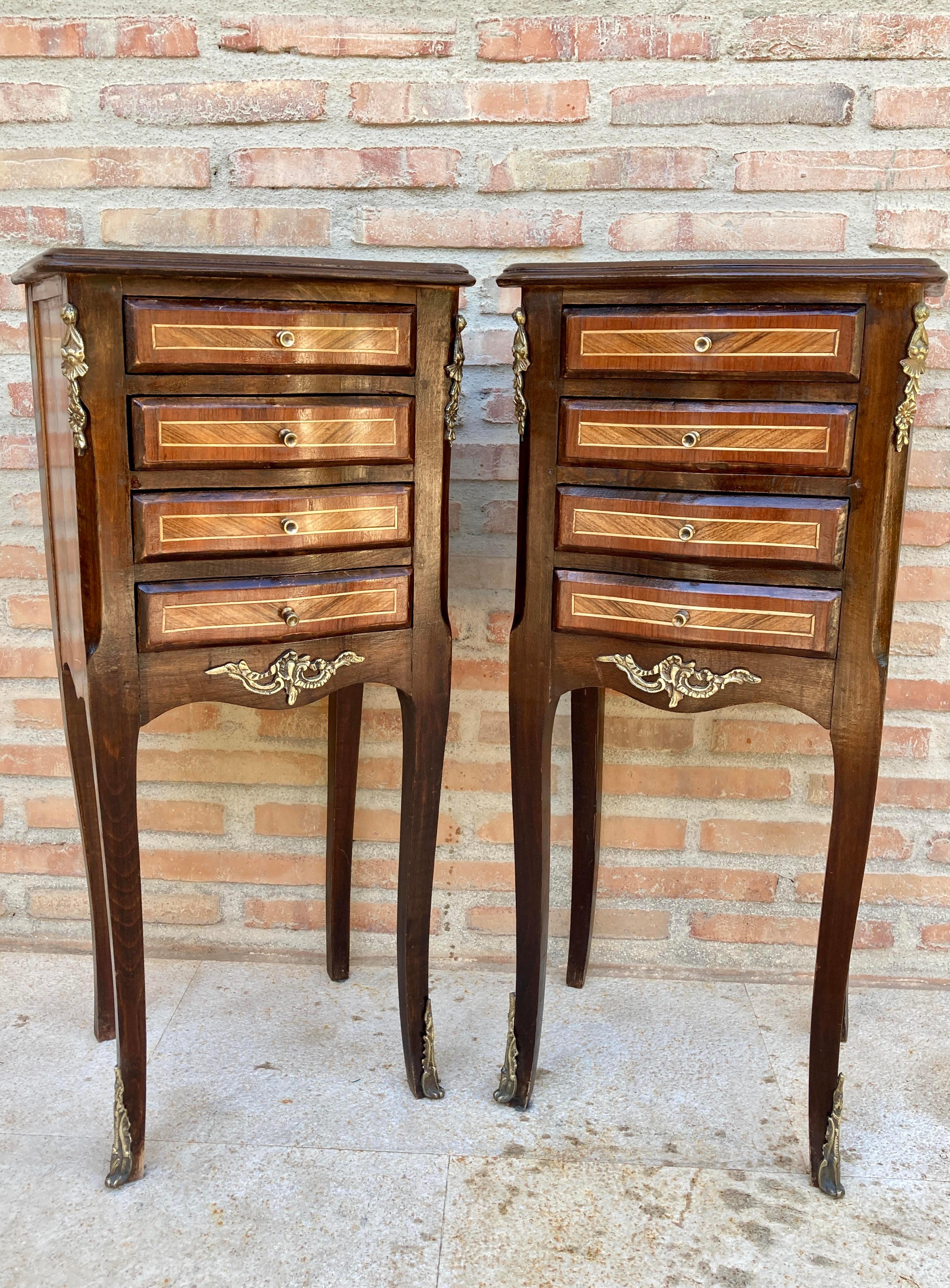 A pair of French Louis XV style nightstands with a marquetry top in TulipWood. The slim body of walnut and tulipwood, each fitted with four drawers with gilt brass-mounted handles and clogs with allegorical gilt-bronze mounts in the corners, Paris,