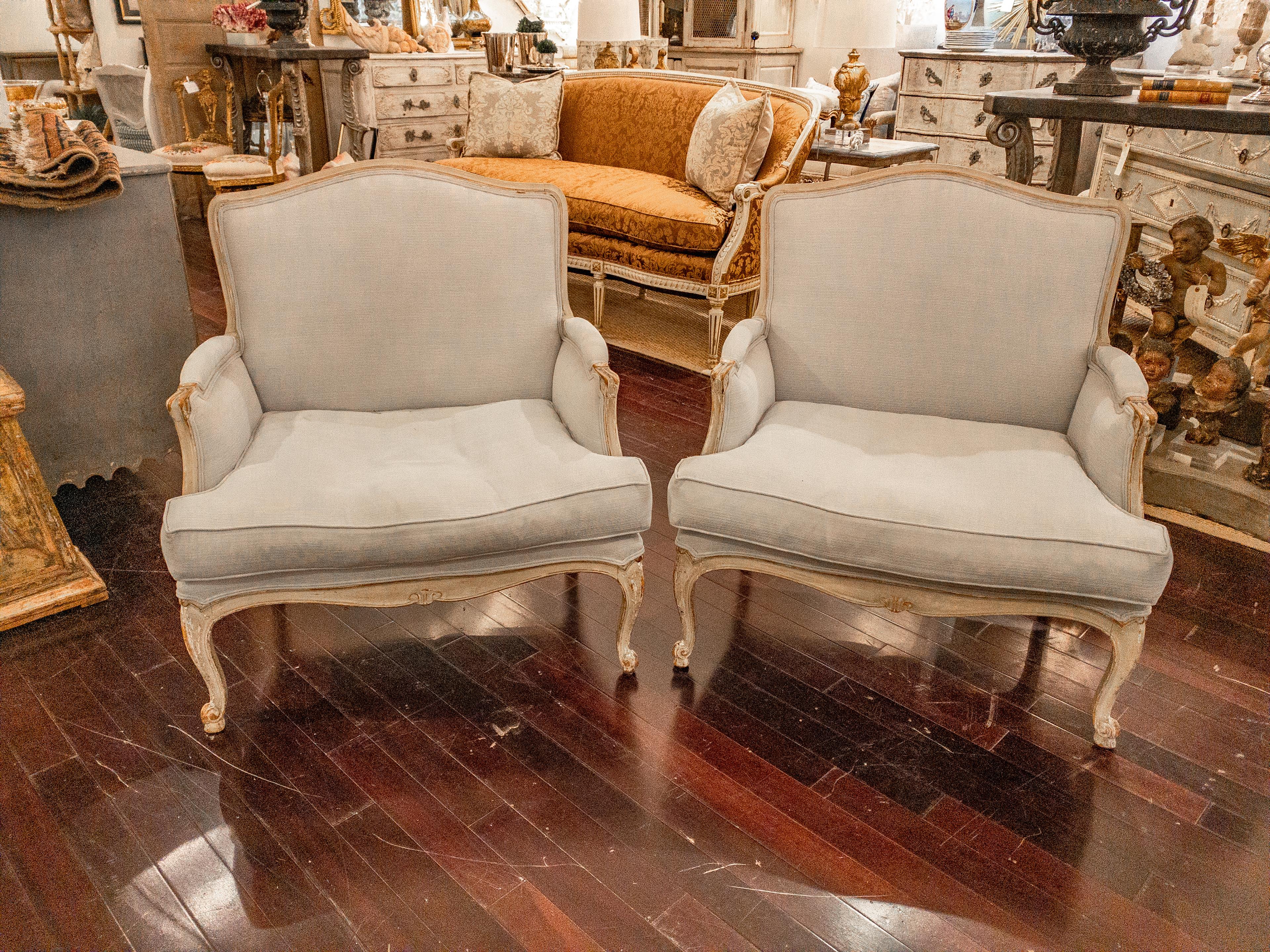 This Pair of French Louis XV Style Upholstered Arm Chairs epitomizes the grace and refinement of the era. Adorned in a newly upholstered grayish sky blue fabric, they exude a sense of tranquility and sophistication, perfectly complementing any