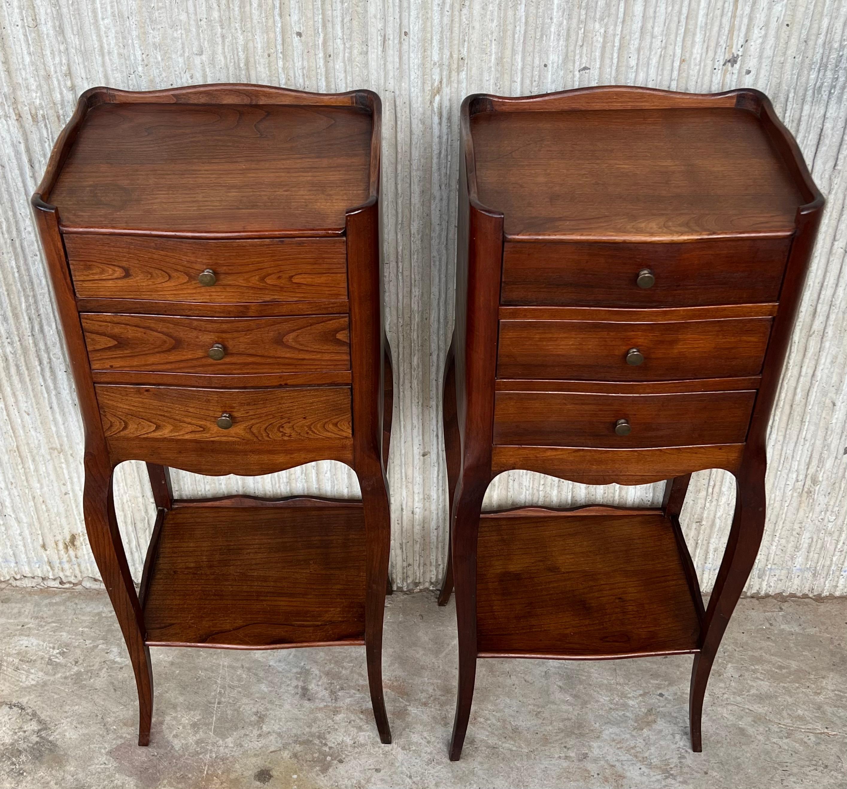 A pair of French Louis XV style walnut bedside tables from the early 20th century. This pair of French 'tables de chevet' was created in the early years of the 20th century, at a time when the country revisited the Rococo style that marked the reign