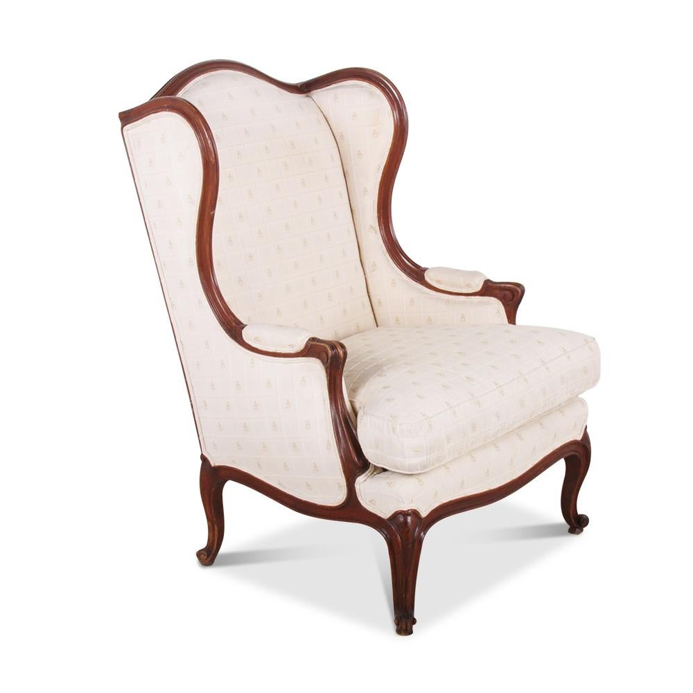 A pair of walnut-framed French Louis XV style wing-back armchairs.

  