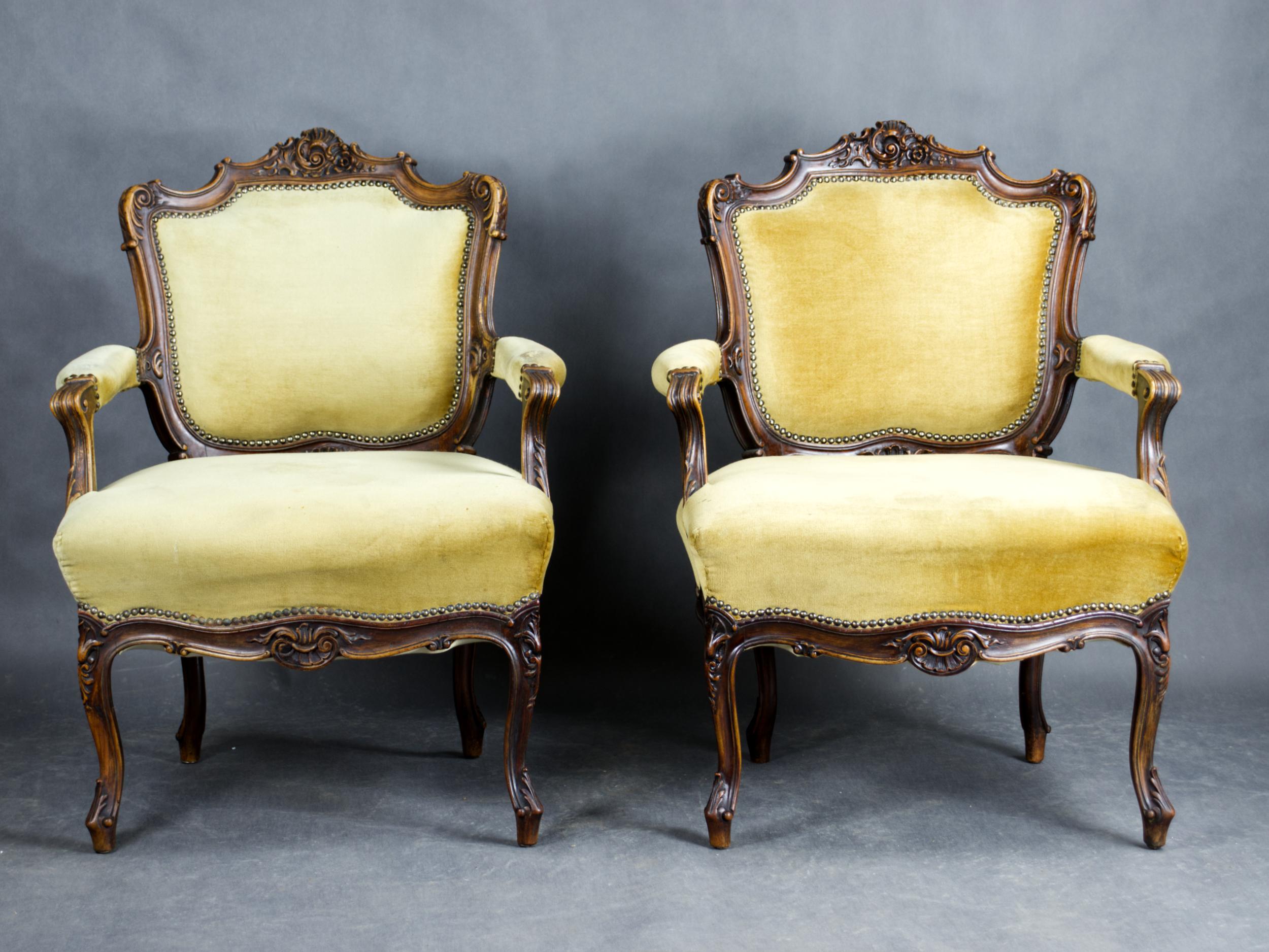 Questa elegante coppia di poltrone francesi esemplifica l'opulenza dello stile Luigi XV, risalente alla seconda metà del XIX secolo (circa 1870). Ogni sedia presenta una struttura in noce finemente intagliata con intricati motivi rocaille e floreali