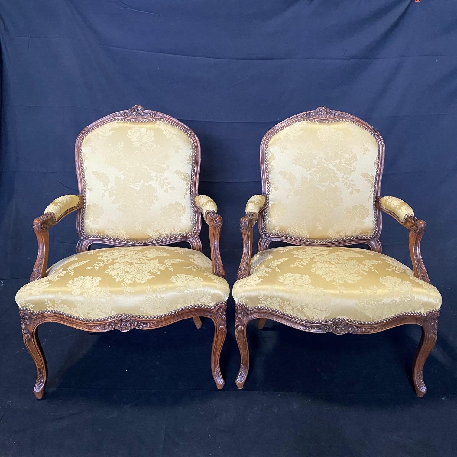 Two lovely and immaculate Louis XV walnut fauteuils or open armchairs, each with a cartouche back, surmounted with intricate high quality floral carving, scrolling arms and shaped seat frames, all raised on cabriole legs. Upholstered in a beautiful