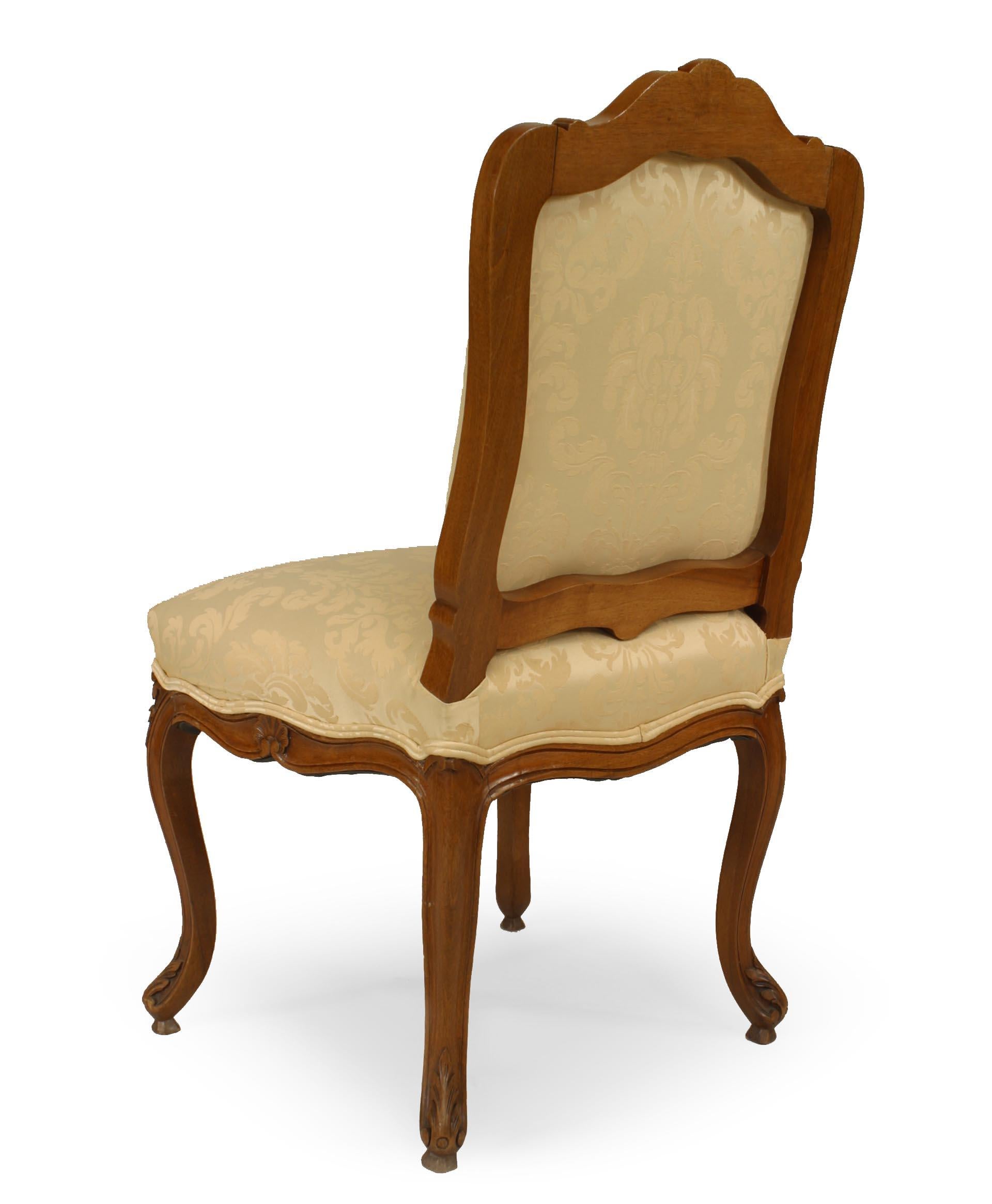 Pair of French Louis XV style (19th Cent) walnut carved side chairs with shaped back and cream upholstered seat and back.
  
