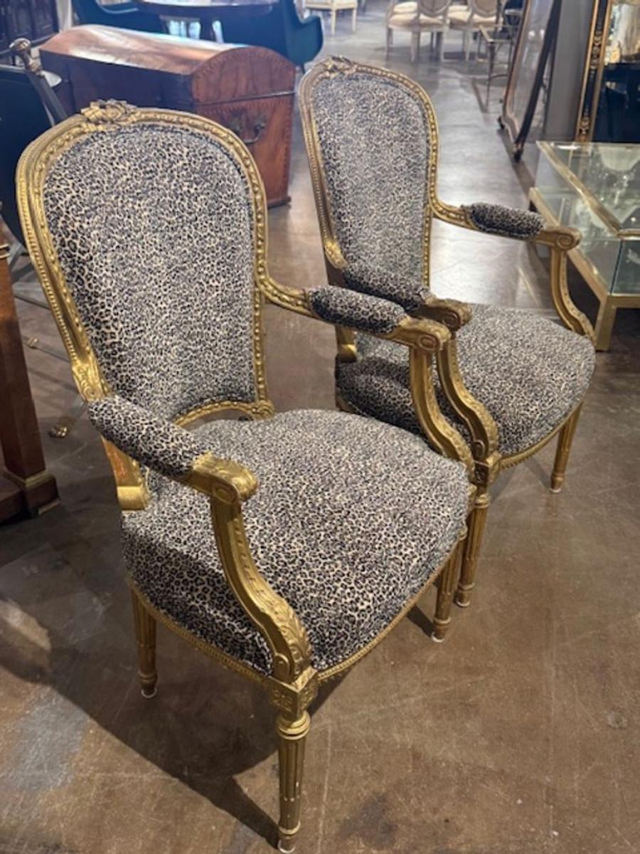 Bonne paire de fauteuils français de style Louis XVI en bois sculpté et doré avec tapisserie léopard. Célèbres pour leur symétrie néoclassique, leurs pieds cannelés et leurs cadres dorés et ornés.  Circa 1940. 23w x 24d x 37.5h