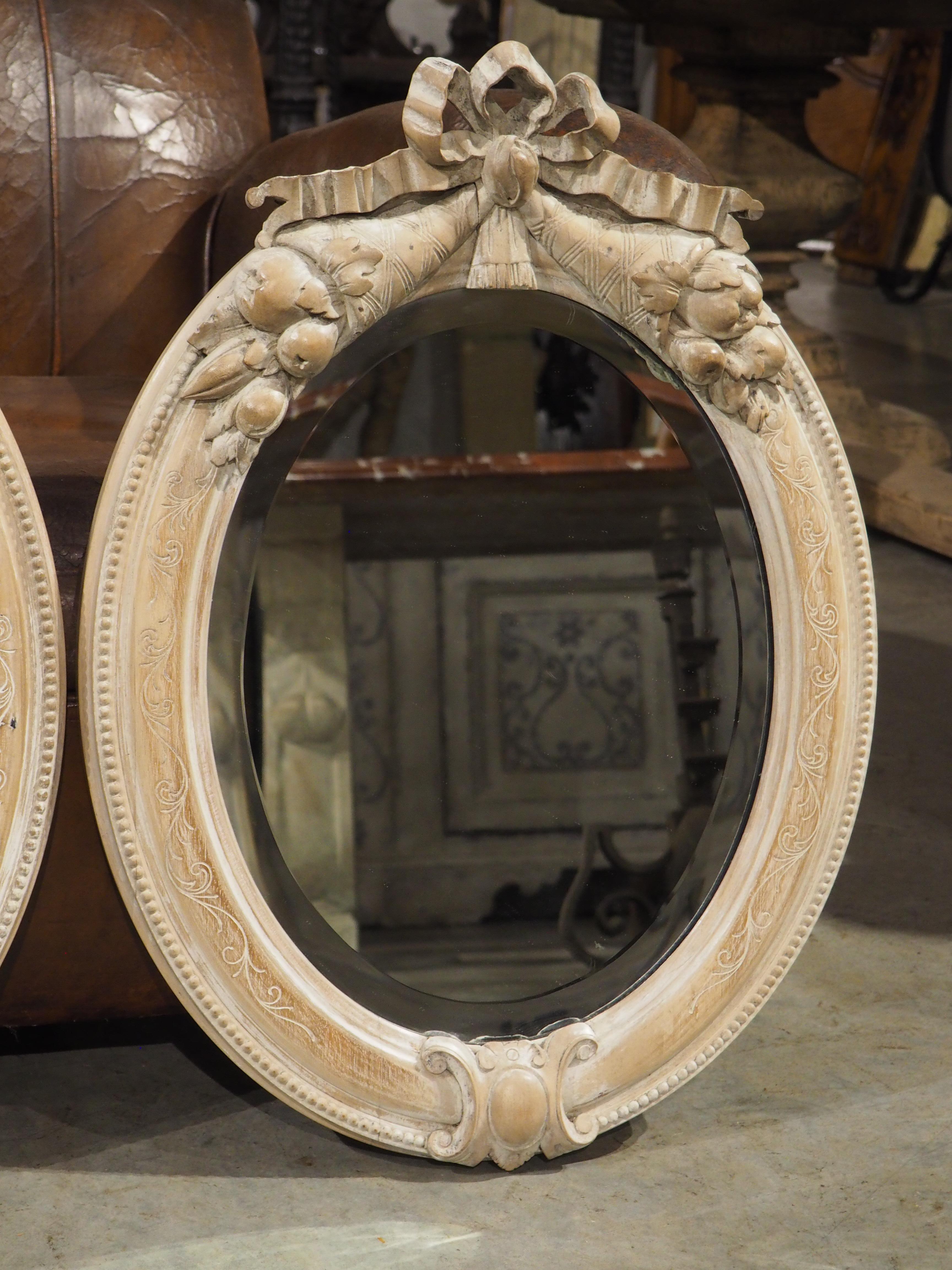 20th Century Pair of French Louis XVI Carved and Whitewashed Wooden Oval Mirrors, Early 1900s