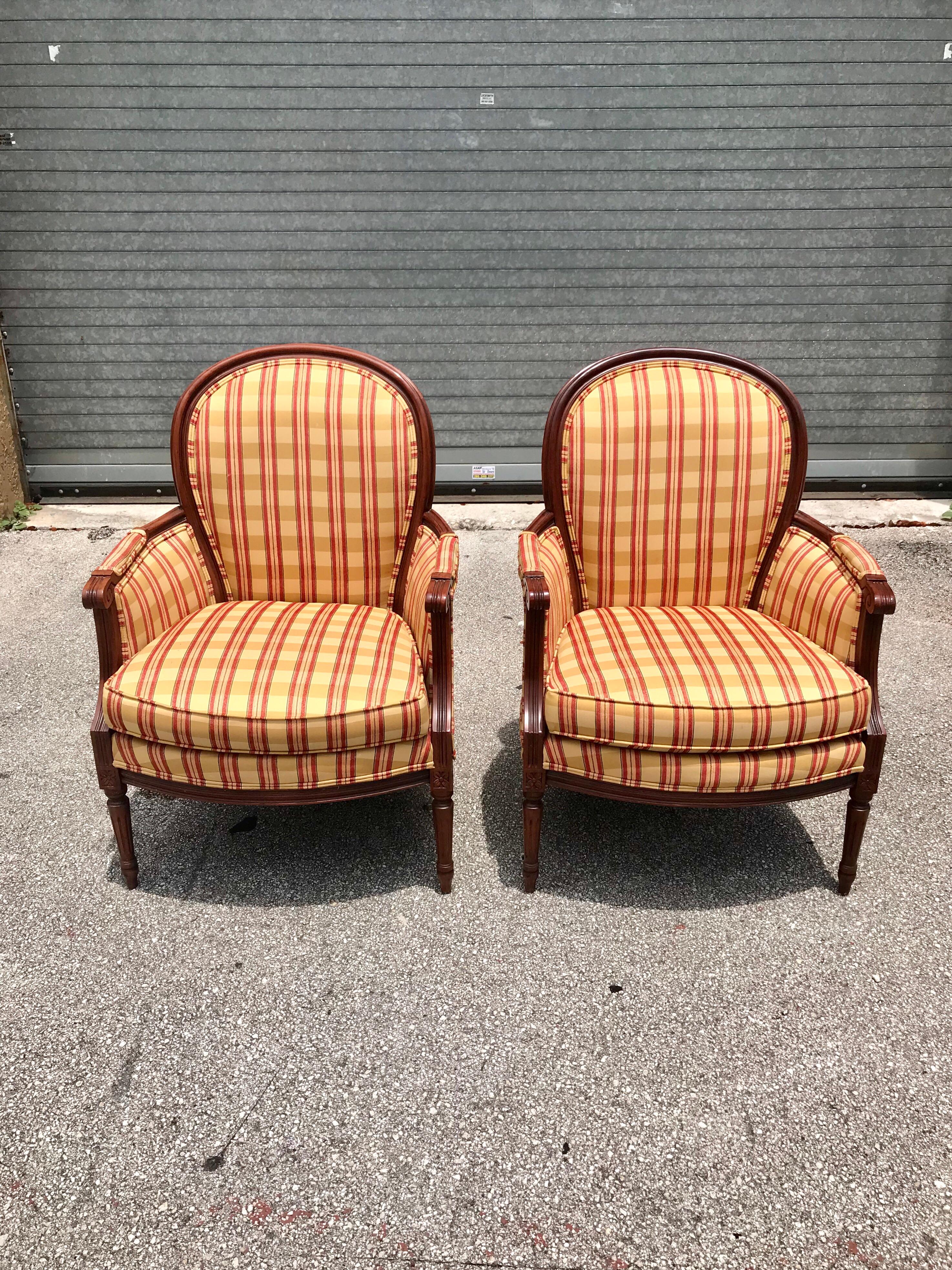 Pair of French Louis XVI accent chairs or Bergère chairs, with stripped upholstery, slightly larger size with padded arms. Subtle carved details on the frames, the fabric is in very good condition, chair frames are in excellent condition, the chairs