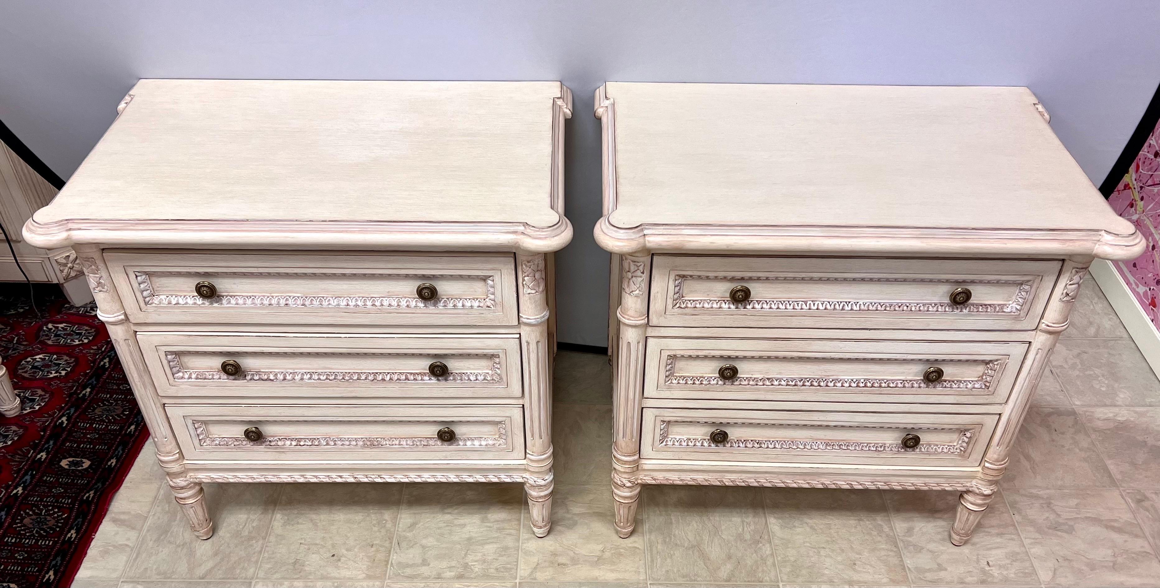 These exquisite nightstands by Louis J. Solomon embody the timeless charm of the Louis XVI style, meticulously crafted with intricate carved details and a beautifully distressed cream finish. With their three spacious drawers, they offer both