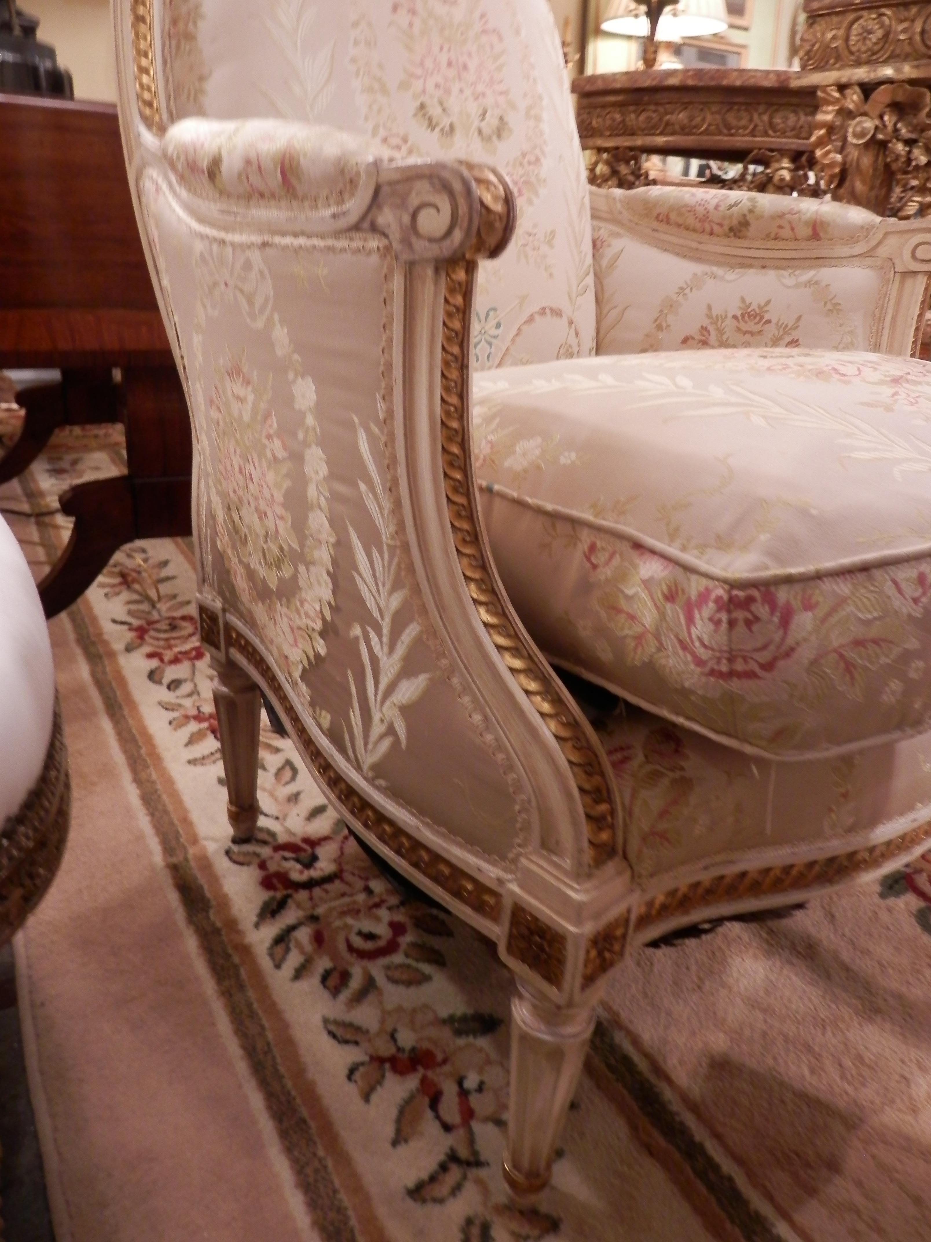 Pair of early 20th century French Louis XVI cream painted and gilt carved bergeres. Covered in a scalamandre silk pattern.