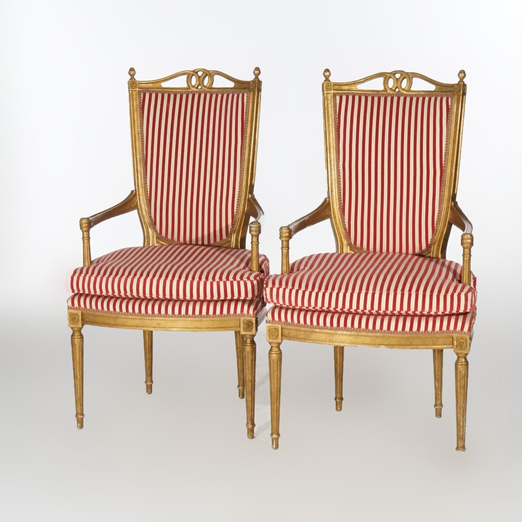 A pair of French Louis XVI style armchairs offer giltwood frames with upholstered backs and seats, shield form backs with flanking finials, raised on tapered turned legs, 20th century

Measures- 44.5''H x 24.5''W x 25.5''D.