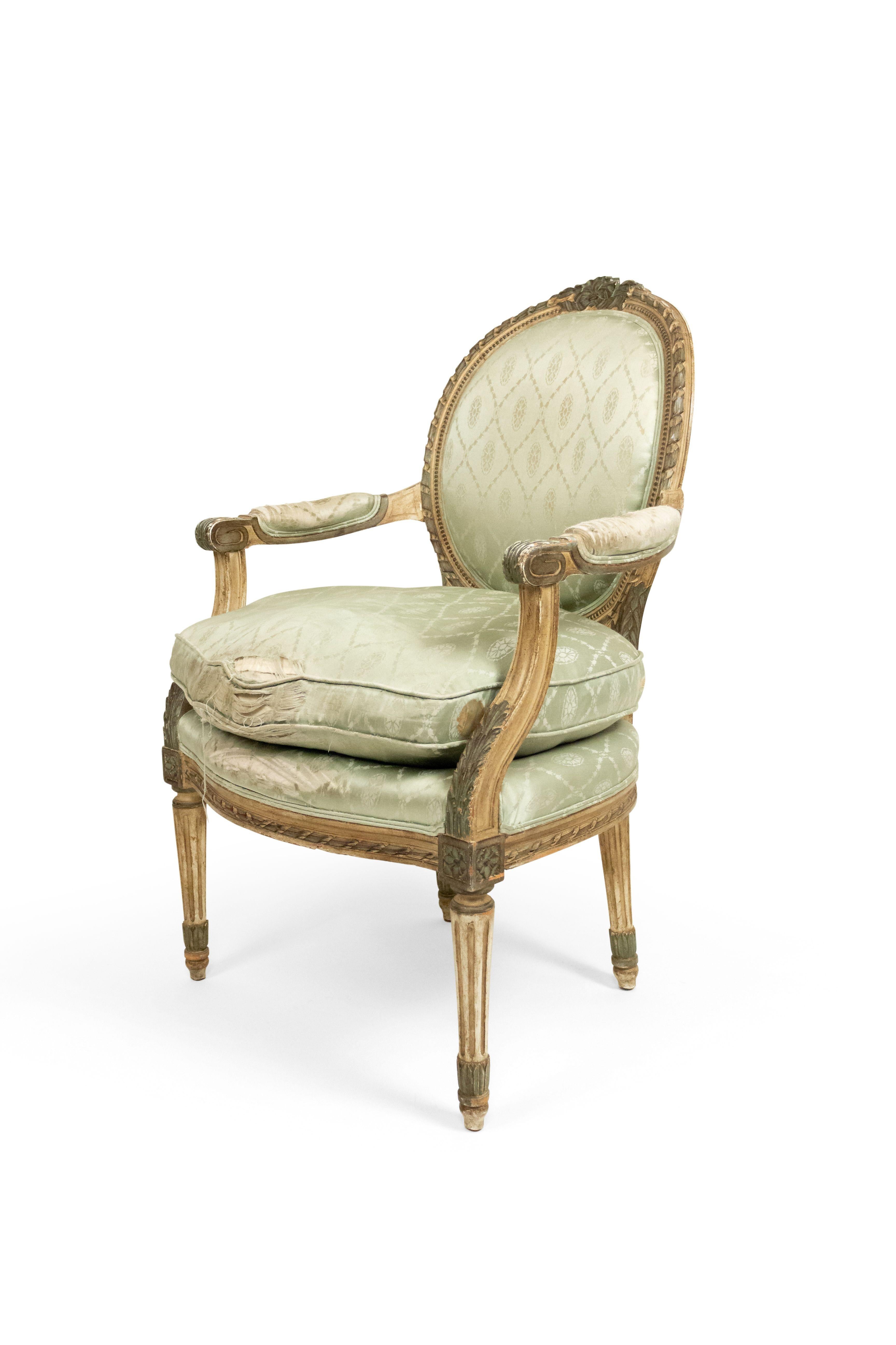Pair of French Louis XVI-style (19th-20th century) grey painted arm chairs with oval back in pale green silk upholstery.