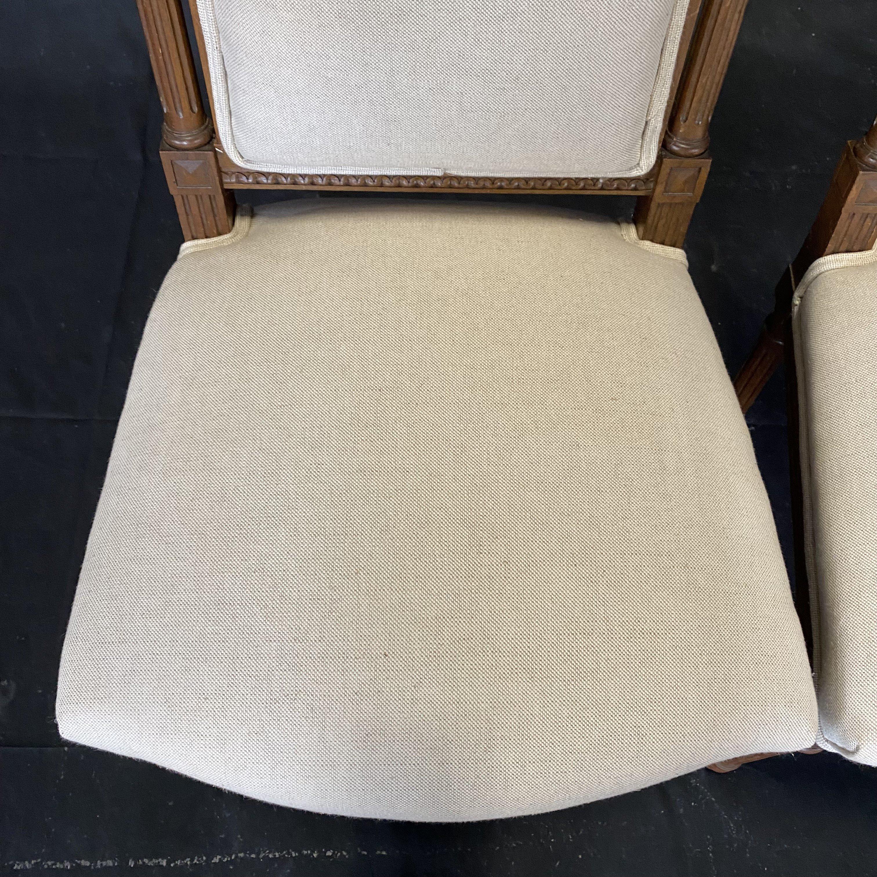 Lovely pair of French side chairs bought in Lyon, France and shipped to the US, where we have reupholstered them in a neutral high quality British linen cotton blend fabric, to highlight the exquisite carving on each chair. The crossed victory