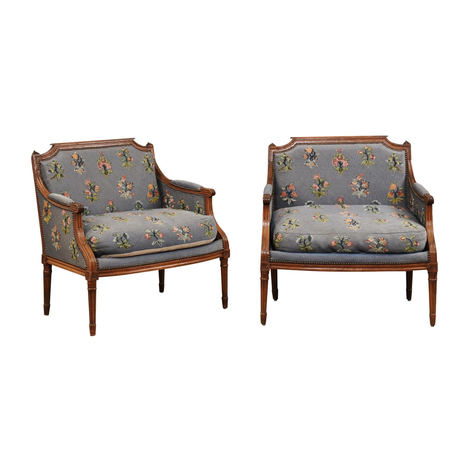 A pair of French Louis XVI period bergères marquises chairs from the late 18th century, with wide seats, carved rosettes, fluted legs and floral upholstery. Created in France during the last decade of the 18th century which saw the end of the
