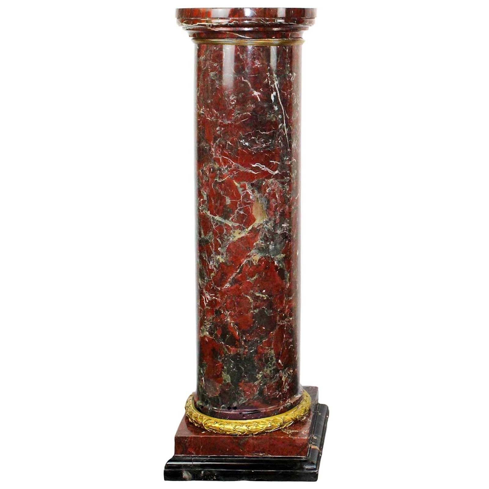 Diese französischen Louis-XVI-Säulen verkörpern zeitlose Eleganz. Sie sind aus exquisitem Rouge-Marmor gefertigt und ihre tiefroten Farbtöne werden durch aufwändige Verzierungen aus vergoldeter Bronze ergänzt. Das kannelierte Design und die