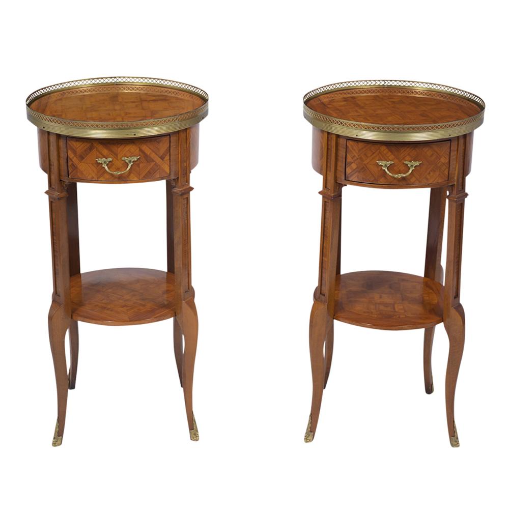 This pair of Vintage French Louis XVI style side tables are made out of solid wood with intricate inlay details and have been newly restored. These tables are decorated with a brass gallery that circles the top, with beautiful inlay design on the