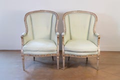 Coppia di sedie Bergères francesi in stile Luigi XVI del 1900 dipinte e dorate a parcella