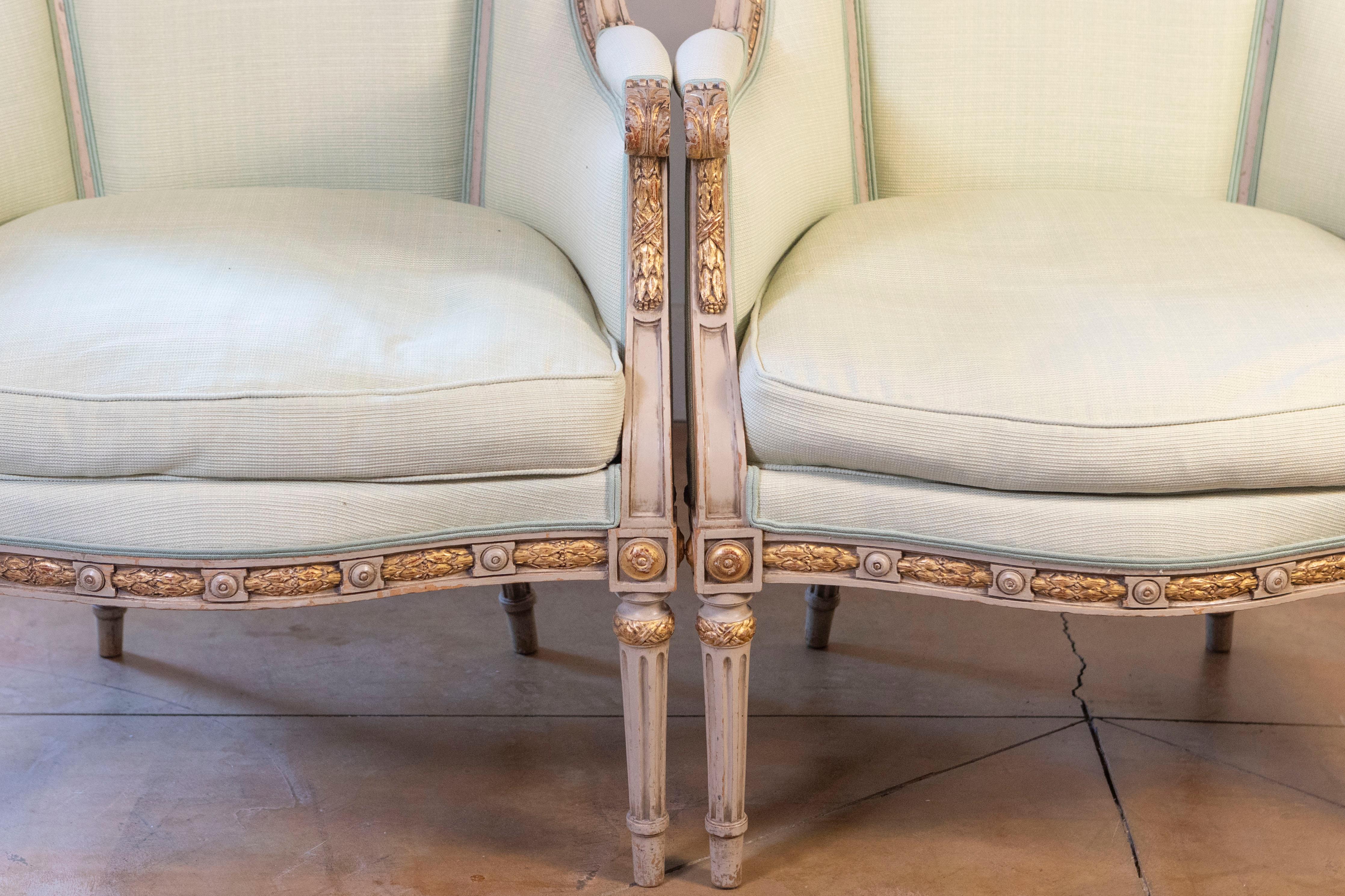 Carved Pair of French Louis XVI Style 1900s Painted and Parcel-Gilt Bergères Chairs For Sale