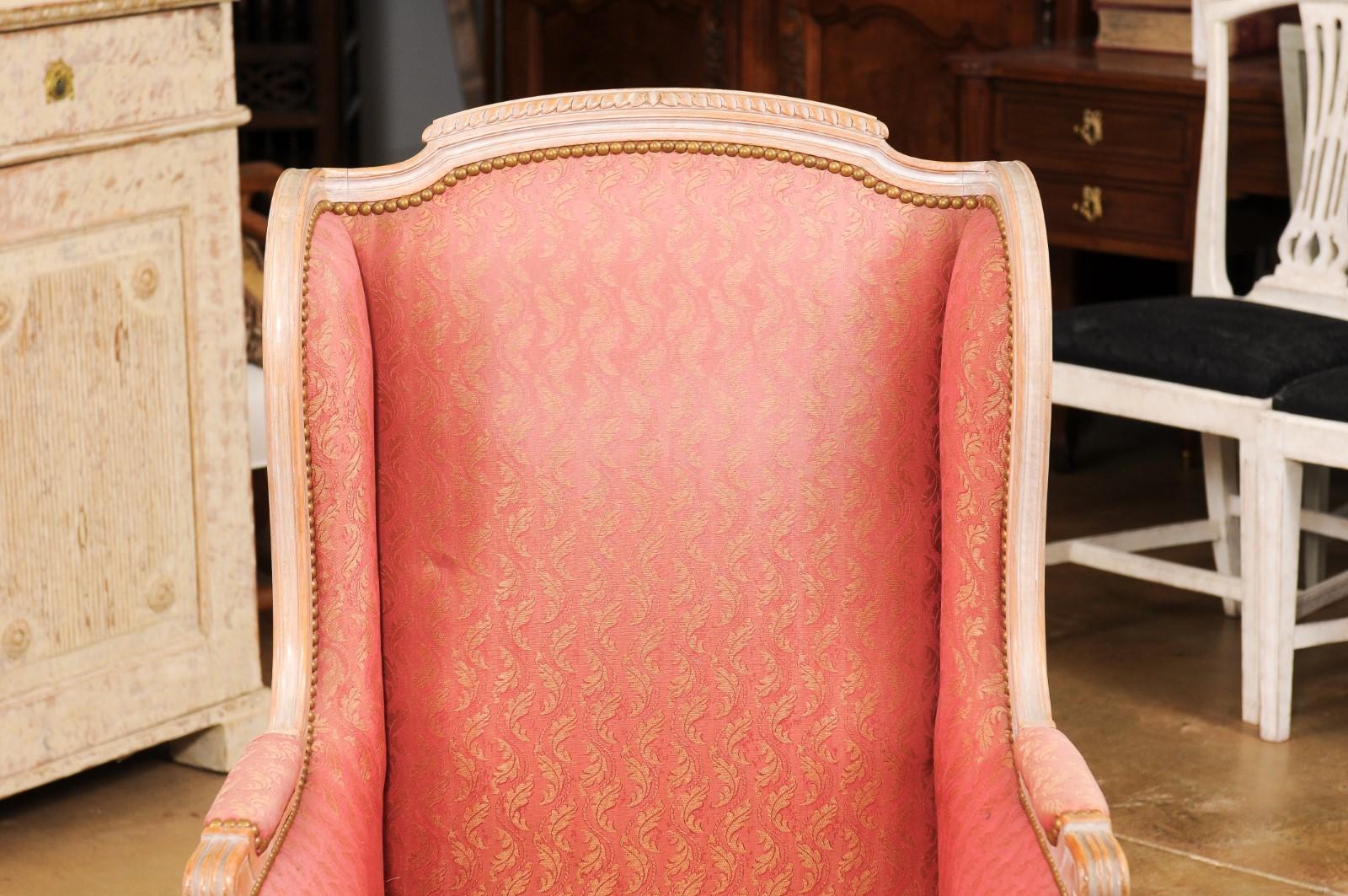 Paire de chaises bergères françaises de style Louis XVI en bois peint du début du 20e siècle, avec décor sculpté et tapisserie à motif de feuillage. Créée en France au tournant du siècle, cette paire de bergères présente les caractéristiques